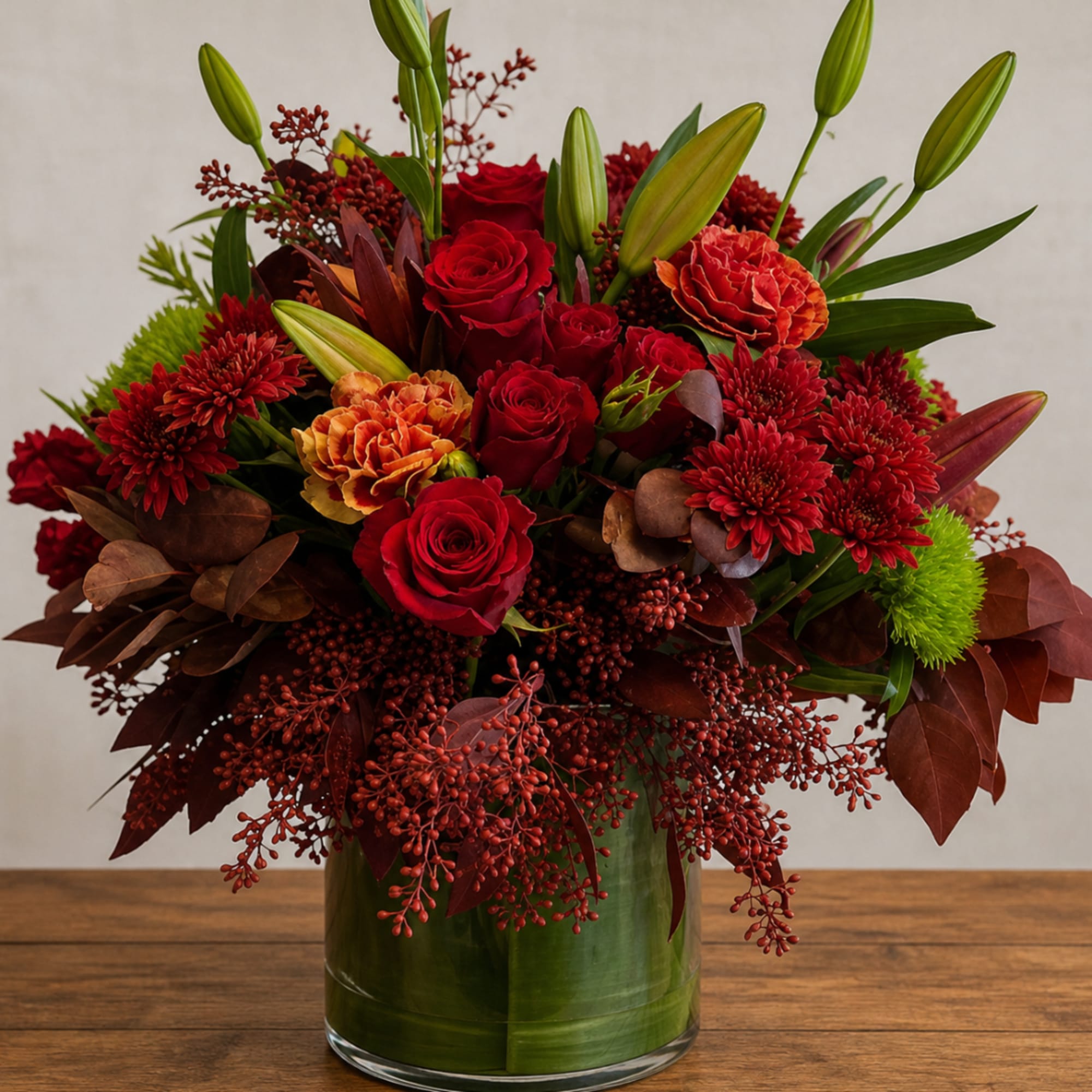 Red roses and orange mums in a green glass vase
