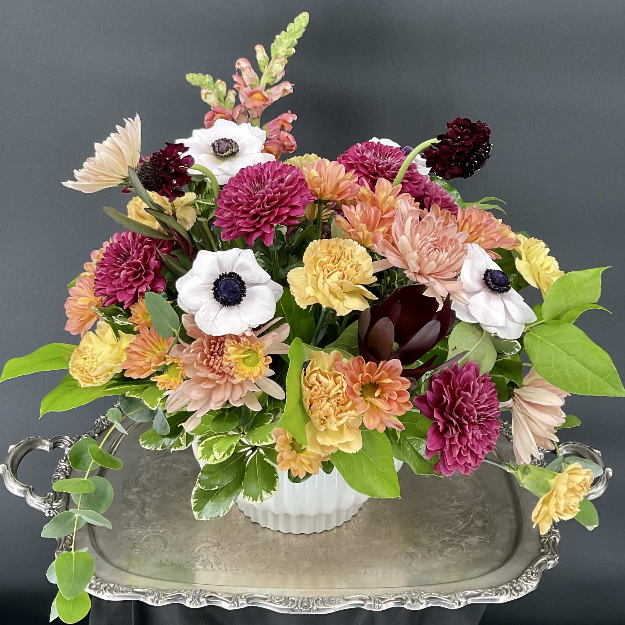 Mixed bouquet of chrysanthemums, carnations, and anemones in a white vase