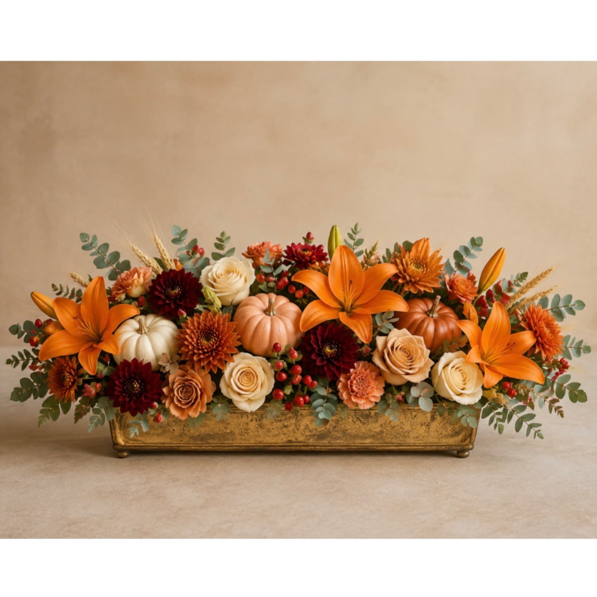 Autumn floral centerpiece with orange lilies and cream roses in a gold planter