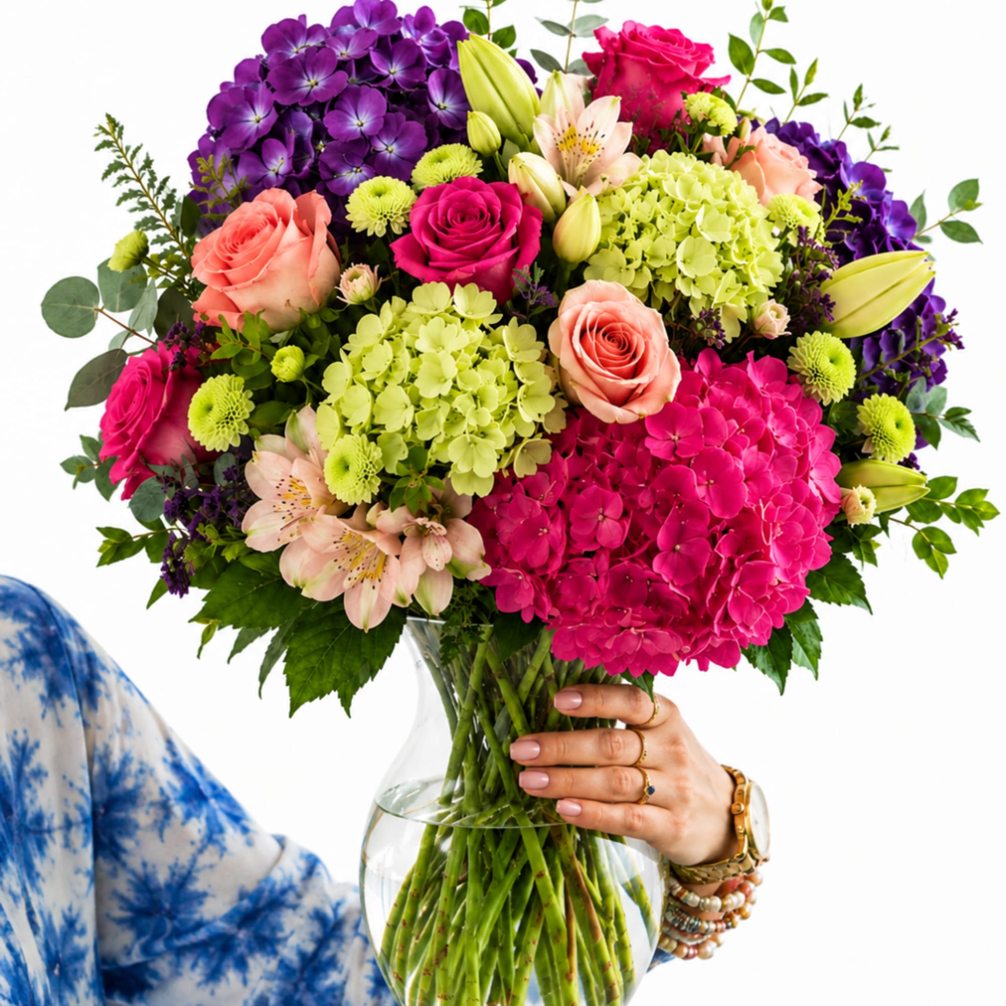 Colorful mixed bouquet in a clear glass vase being held by a person