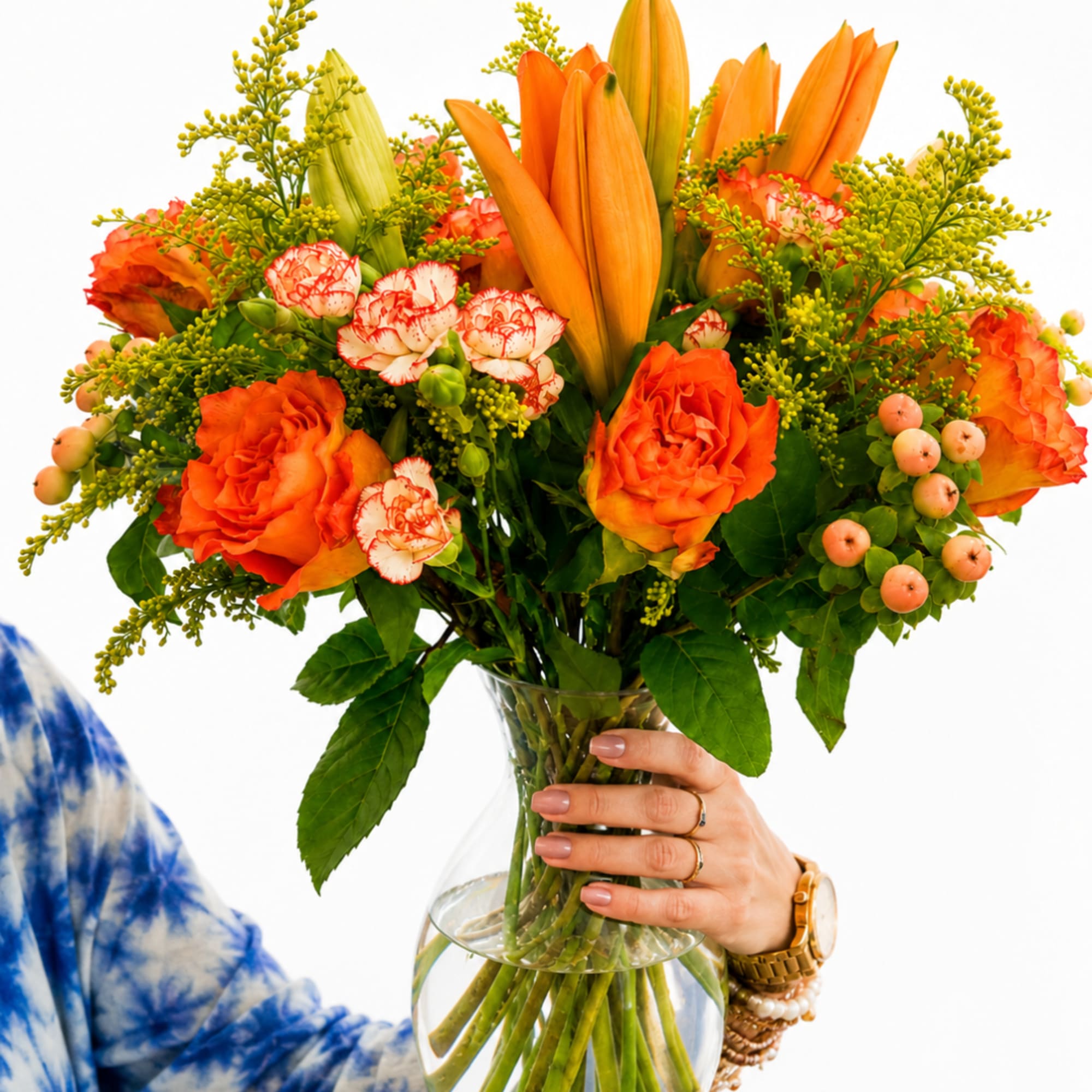 Orange bouquet with lilies, roses, and carnations in a clear glass vase