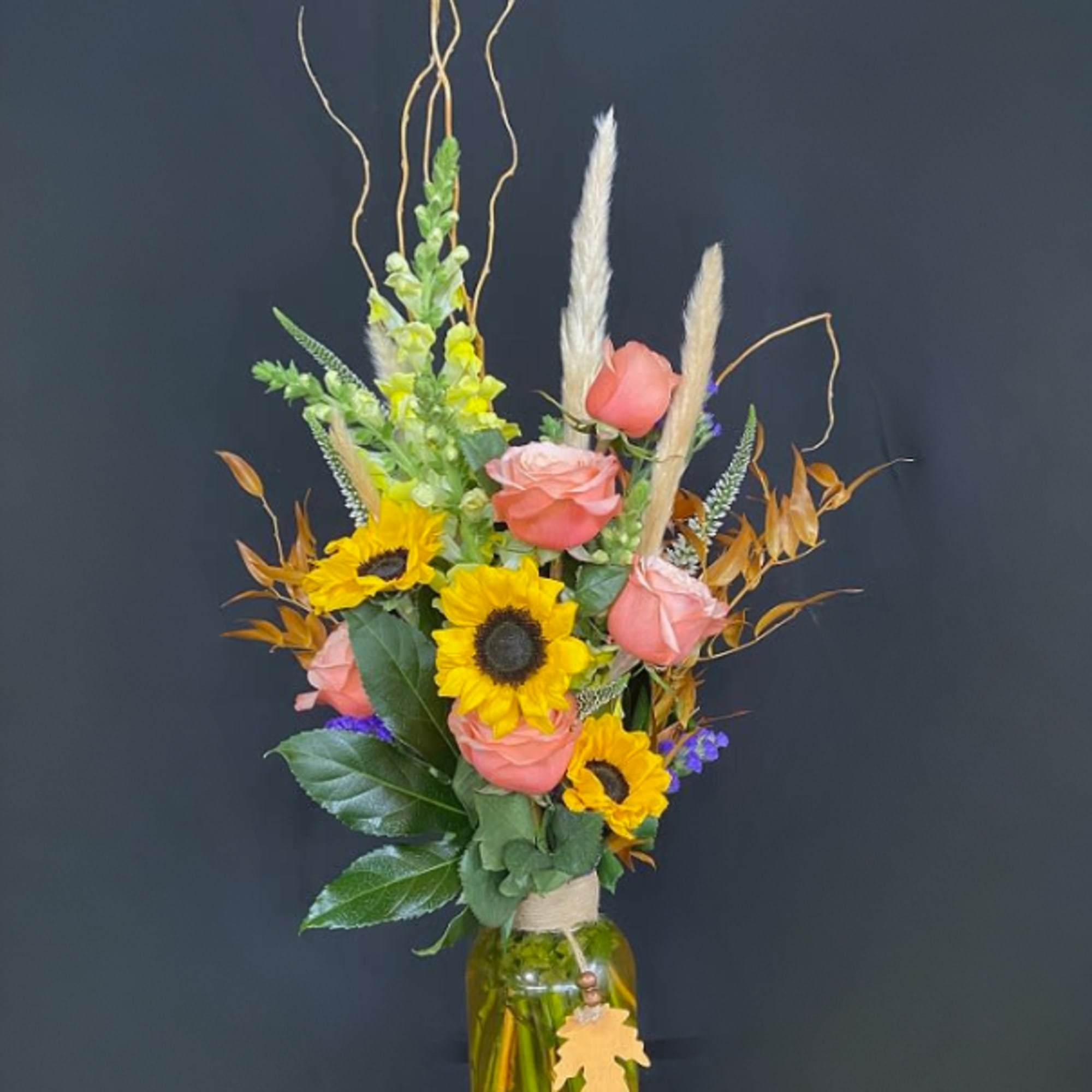 Tall bouquet of sunflowers and pink roses in a glass vase
