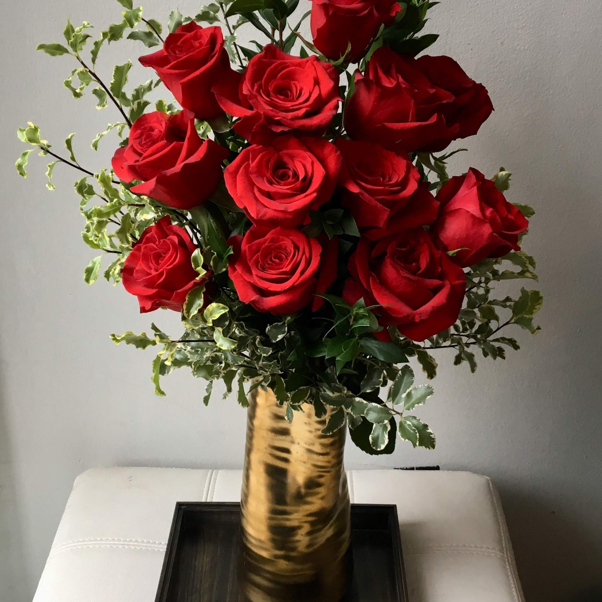 A lush cluster of deep red roses arranged in a gleaming metallic