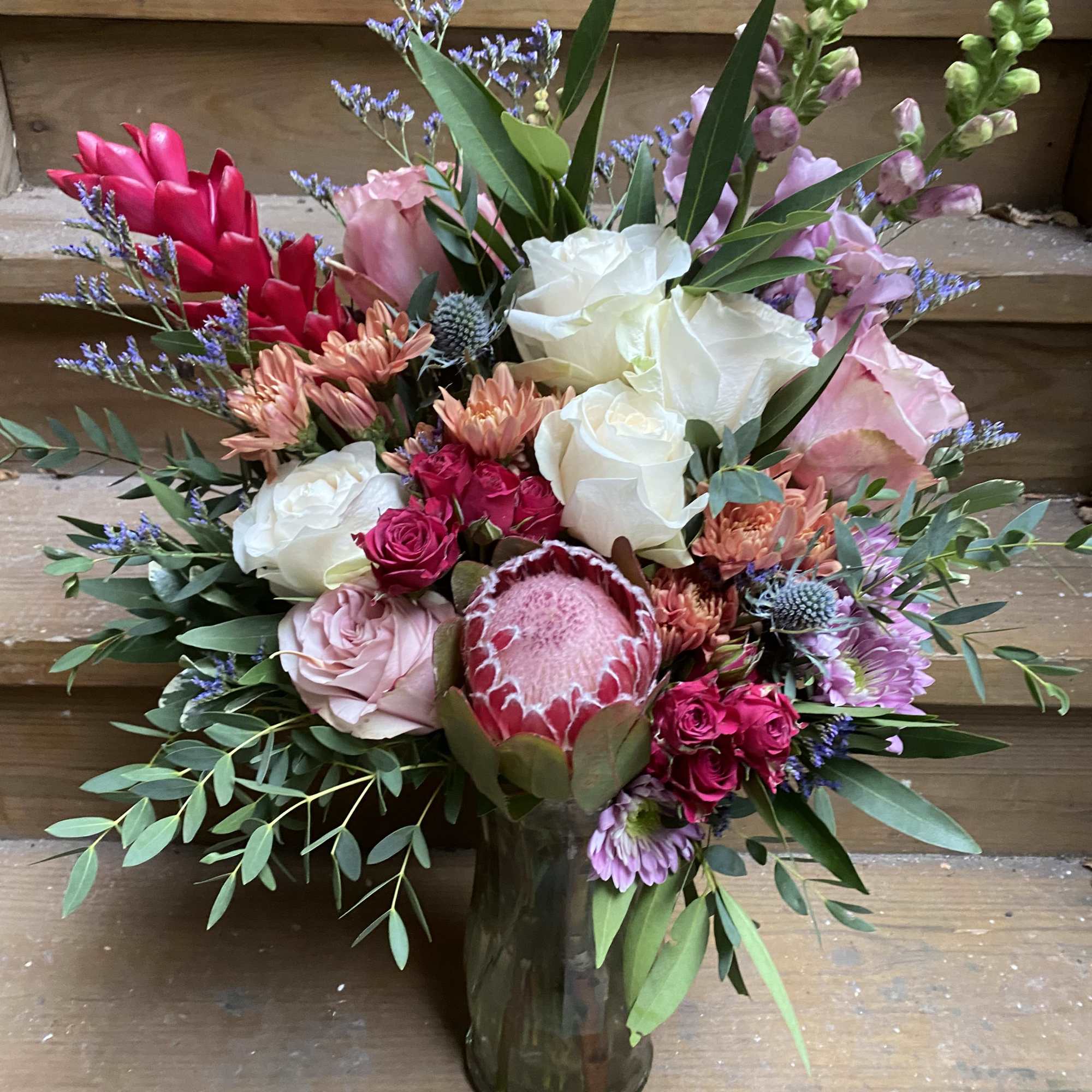 Mixed bouquet of pink, white, and red flowers in a glass vase