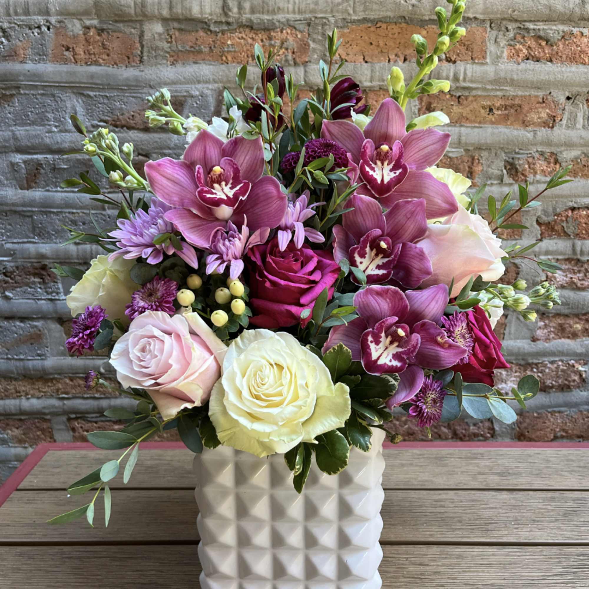 Mixed bouquet of pink orchids and roses in a white vase