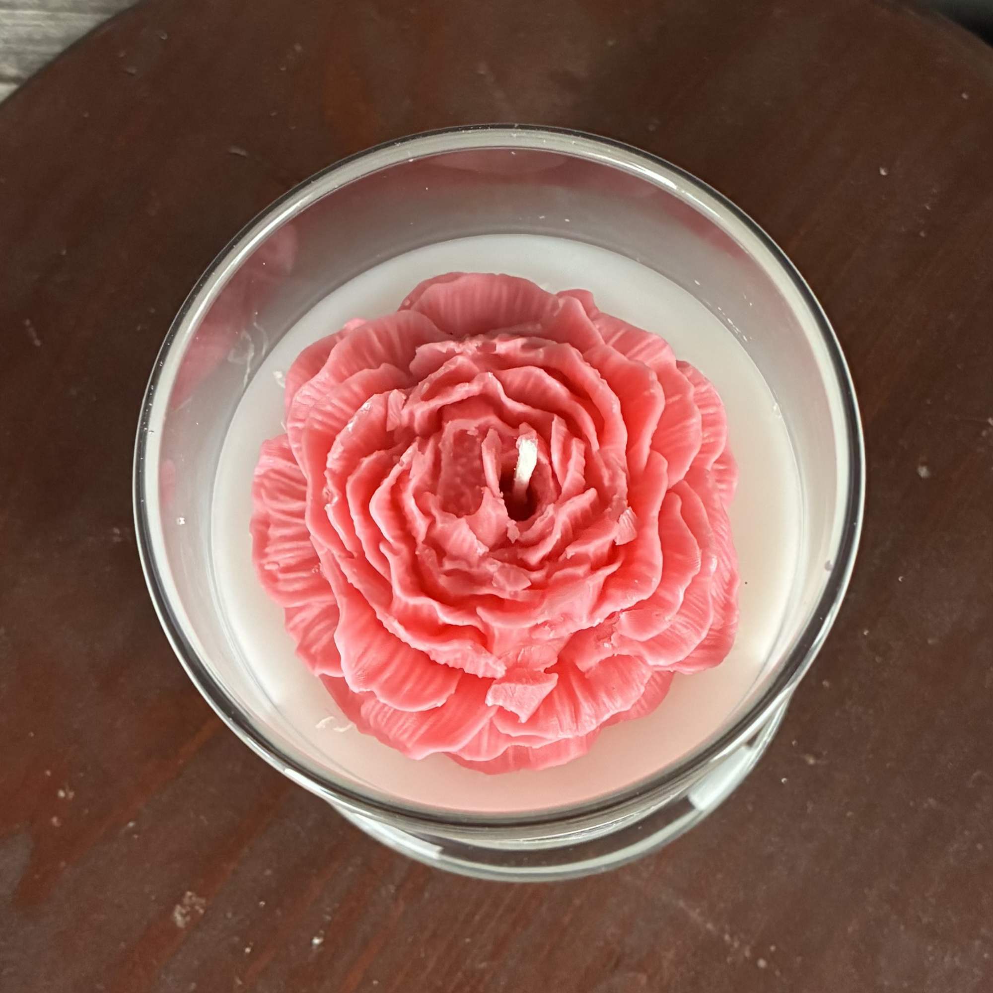 Glass jar candle with a carved pink flower-shaped top on white wax