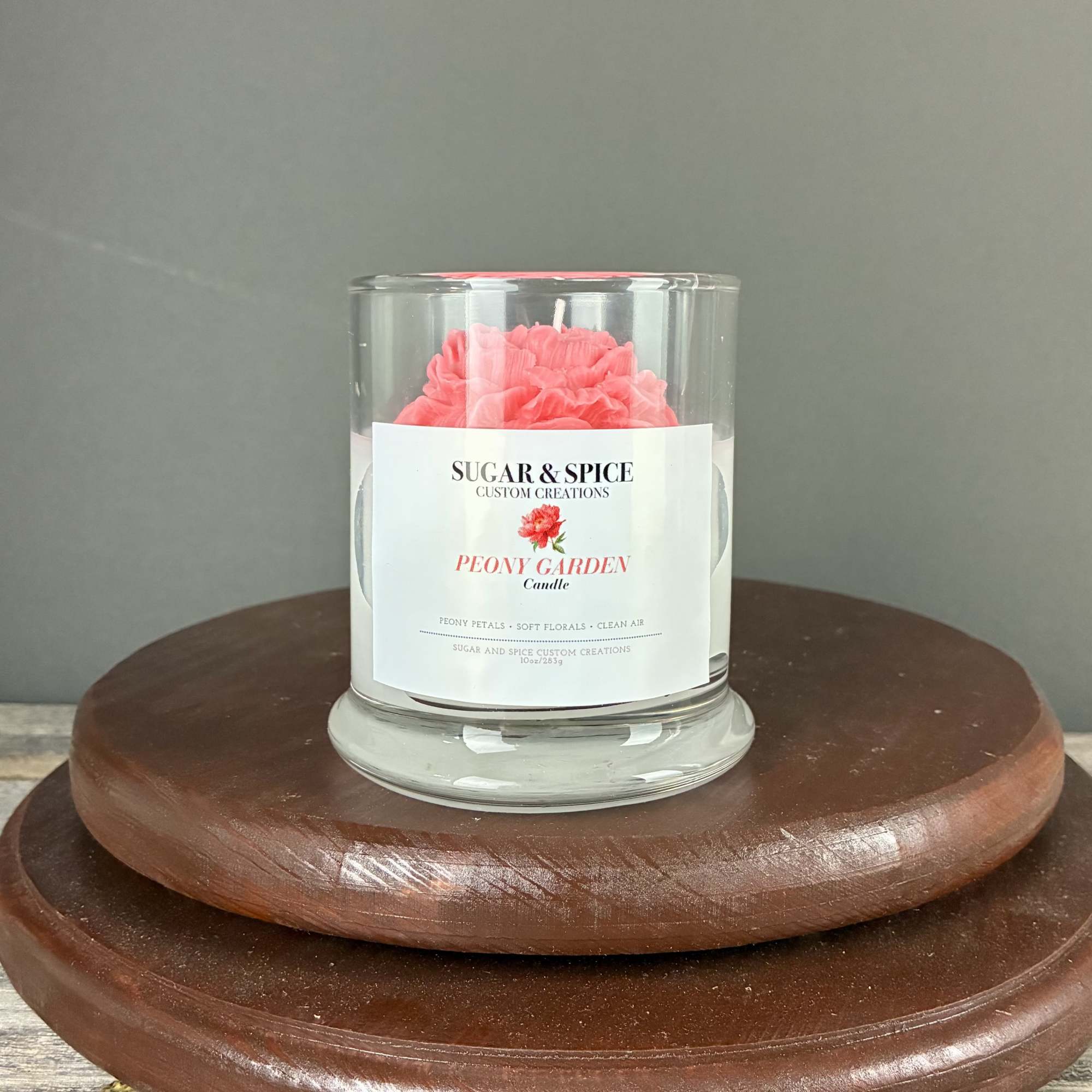 Glass Peony Garden candle with pink wax flower on a wooden stand