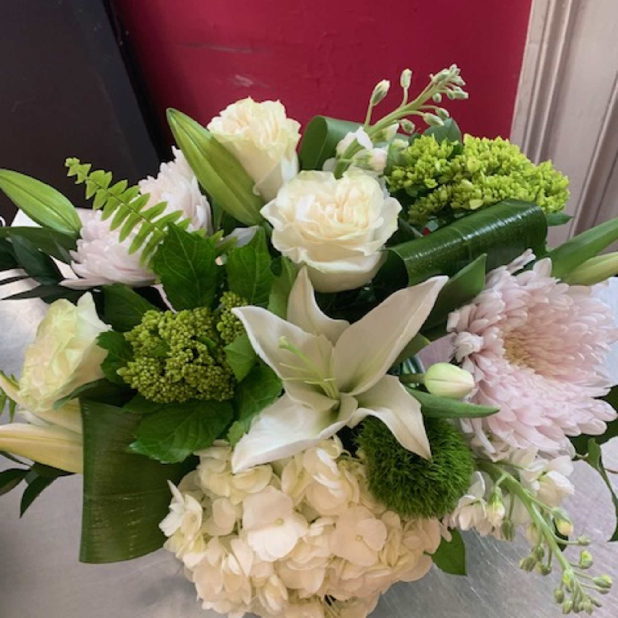 White and pale pink bouquet with lilies, roses, hydrangea, and green accents