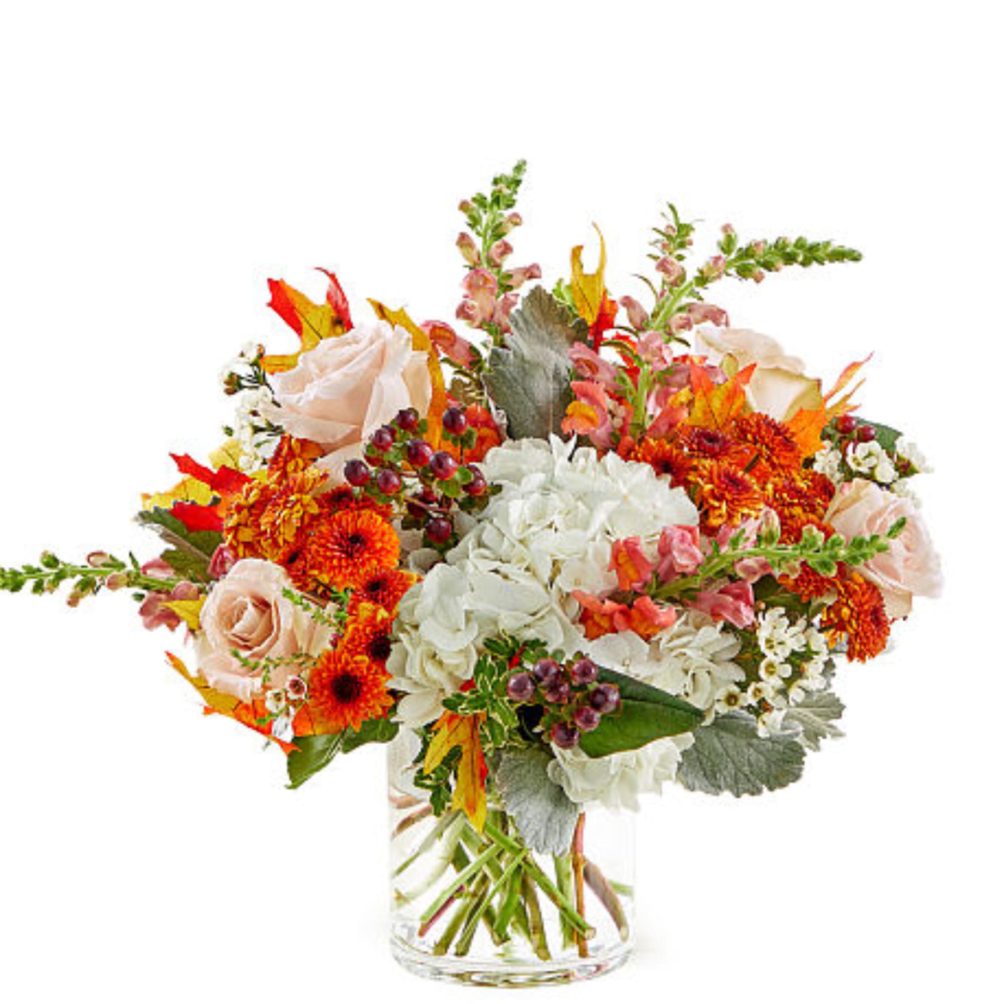 Mixed bouquet of orange, white, and blush flowers in a clear glass vase