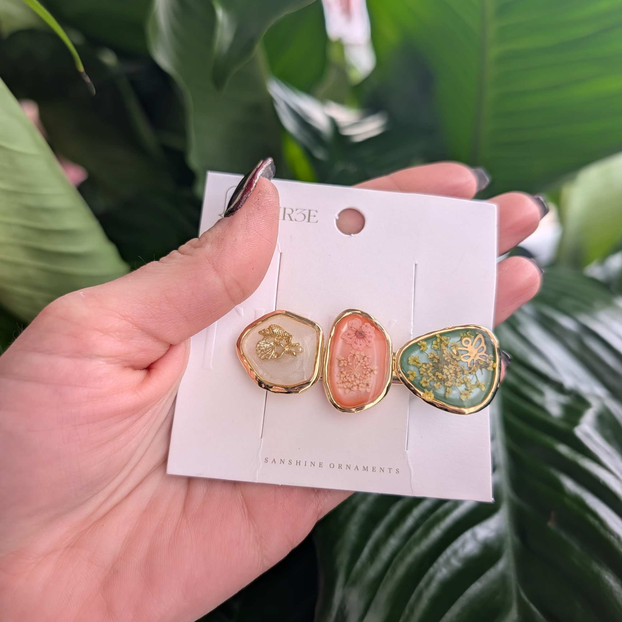 Hand holding a card with three floral resin hair clips