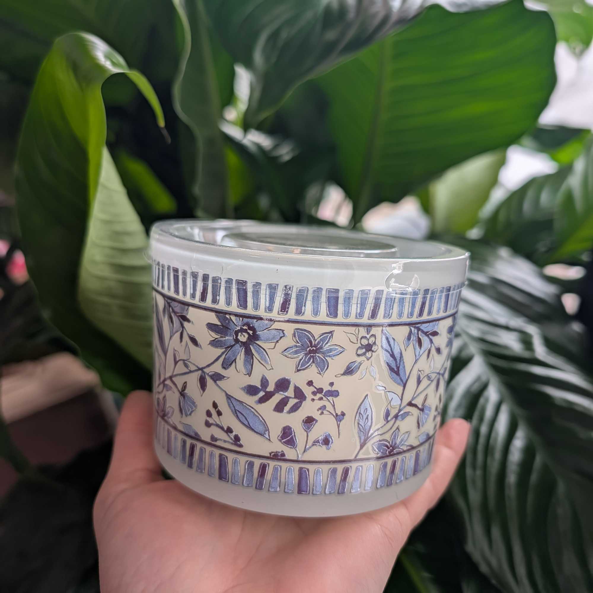 Decorative floral-patterned candle tin held in a hand