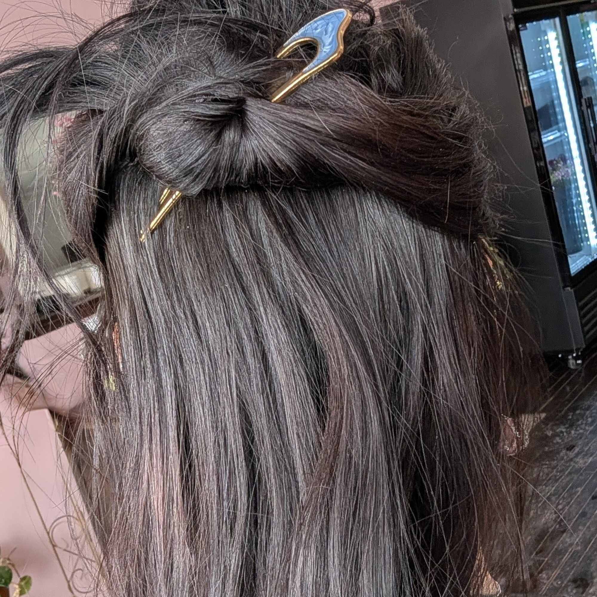Dark hair styled with a decorative blue-and-gold hair clip