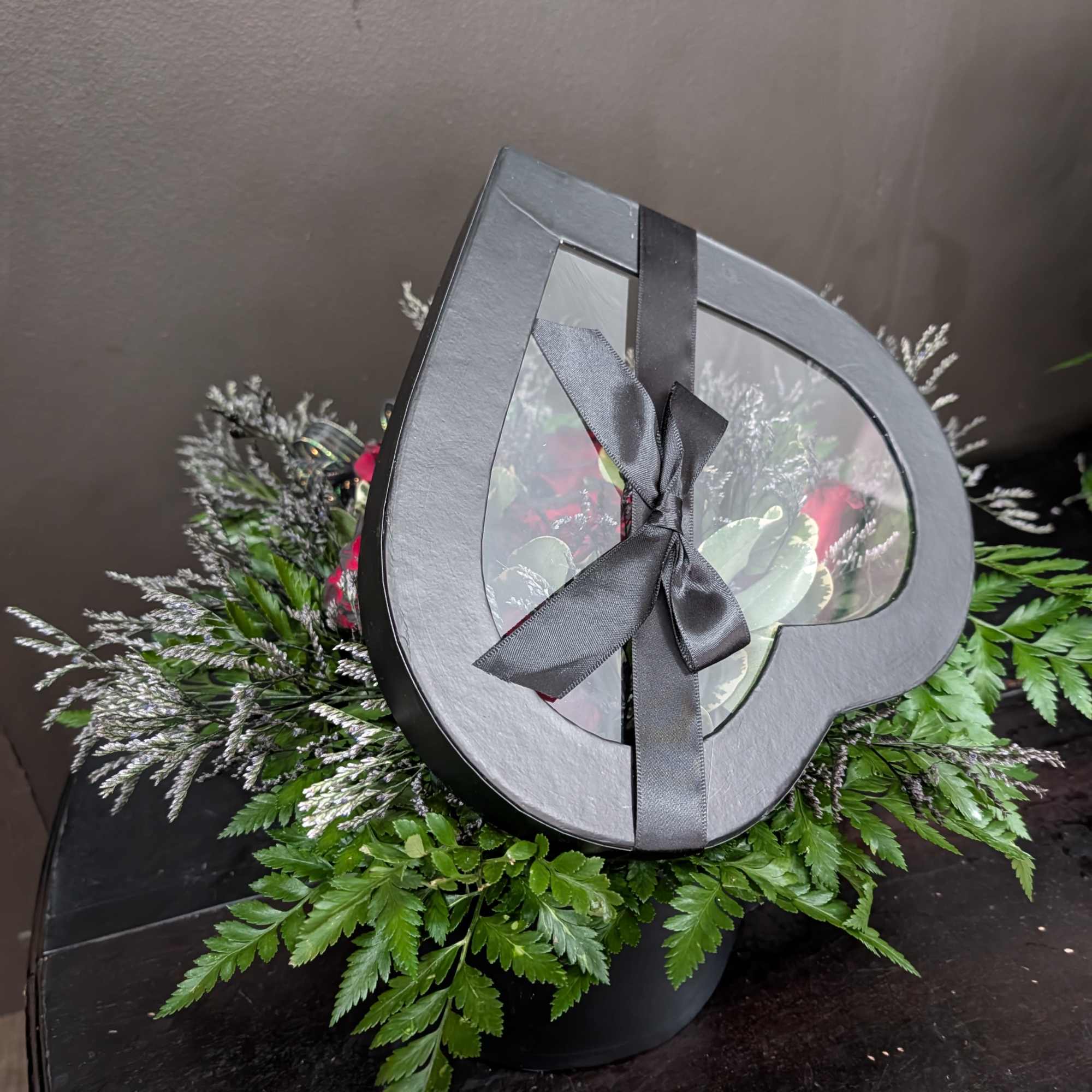 Heart-shaped floral box with a black ribbon and mixed flowers