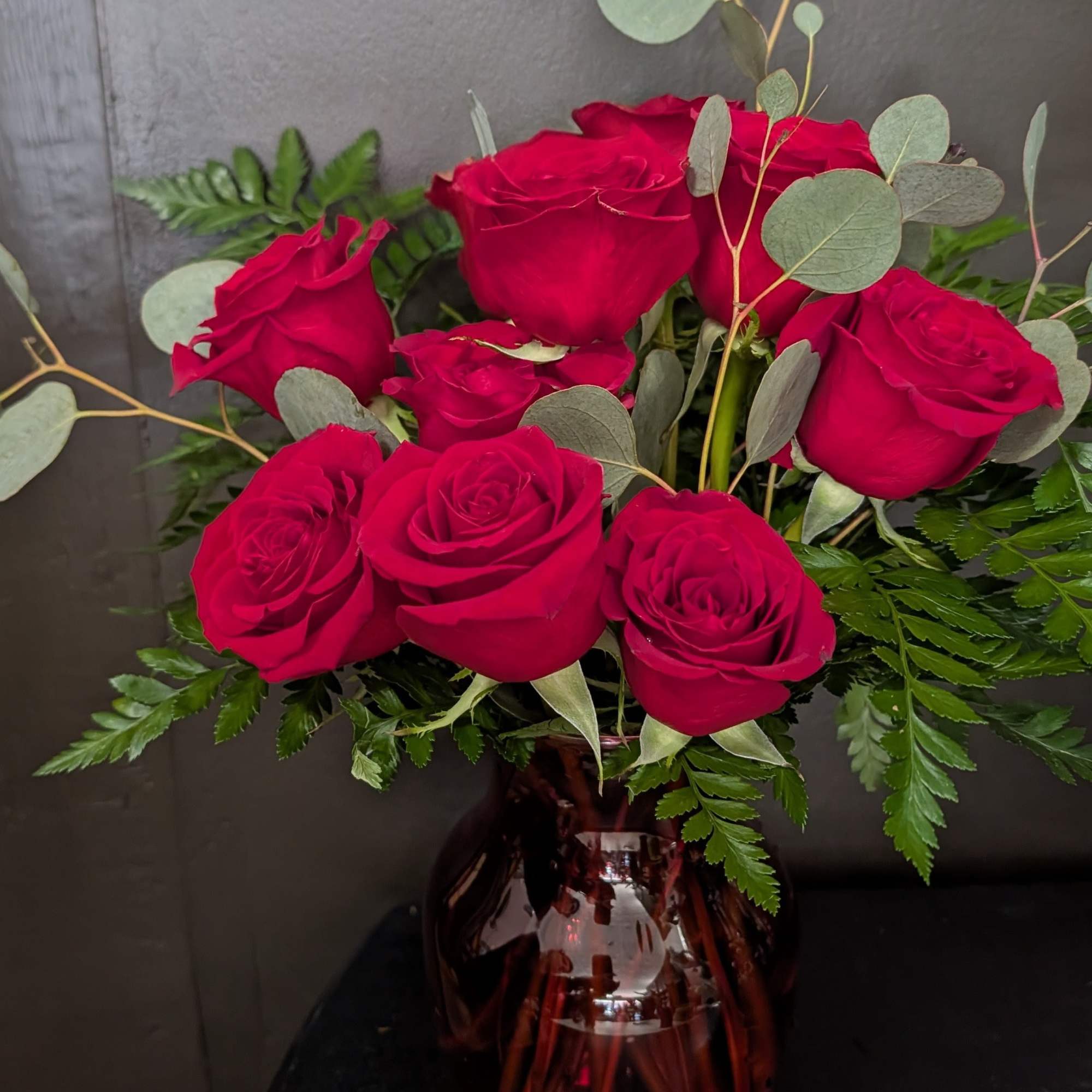 Bouquet of red roses in a burgundy glass vase