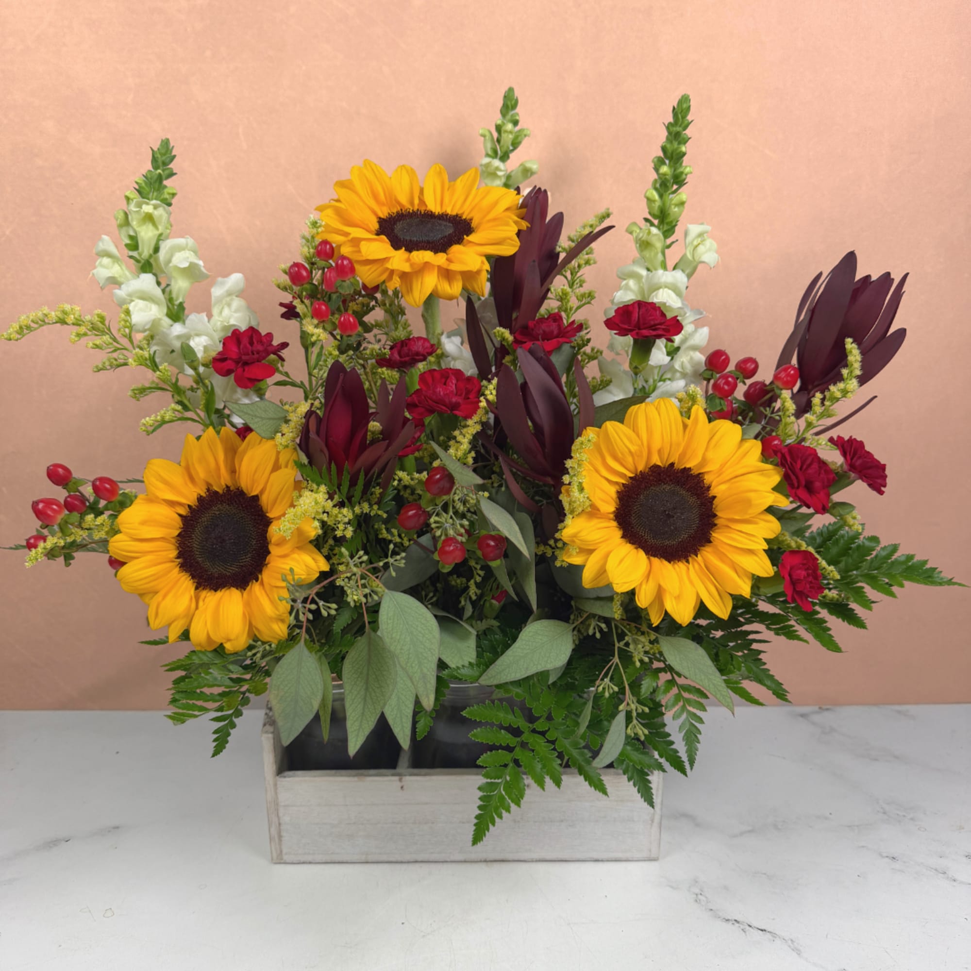 Sunflower arrangement with red carnations in a wooden box