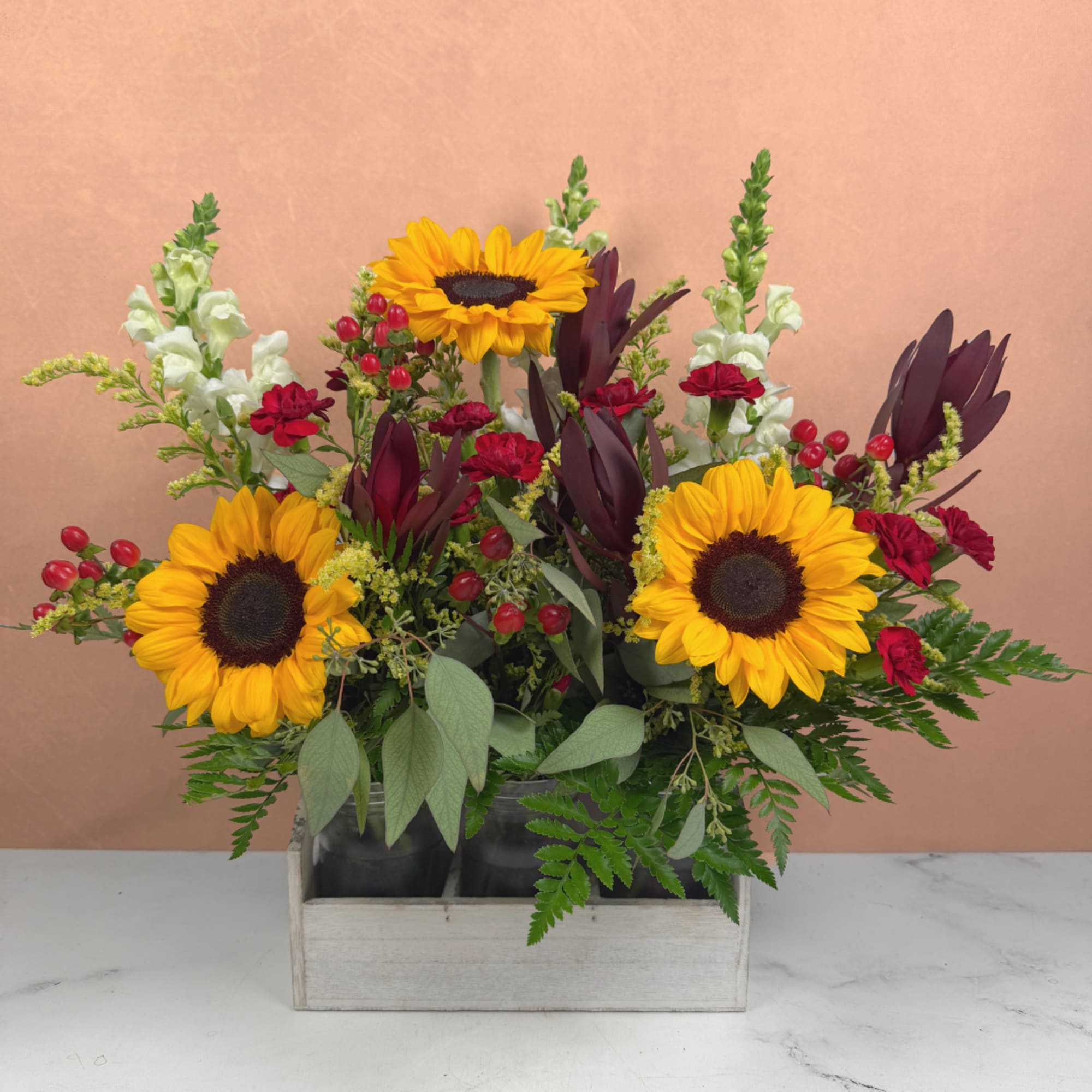 Sunflowers and red carnations arranged in a wooden box