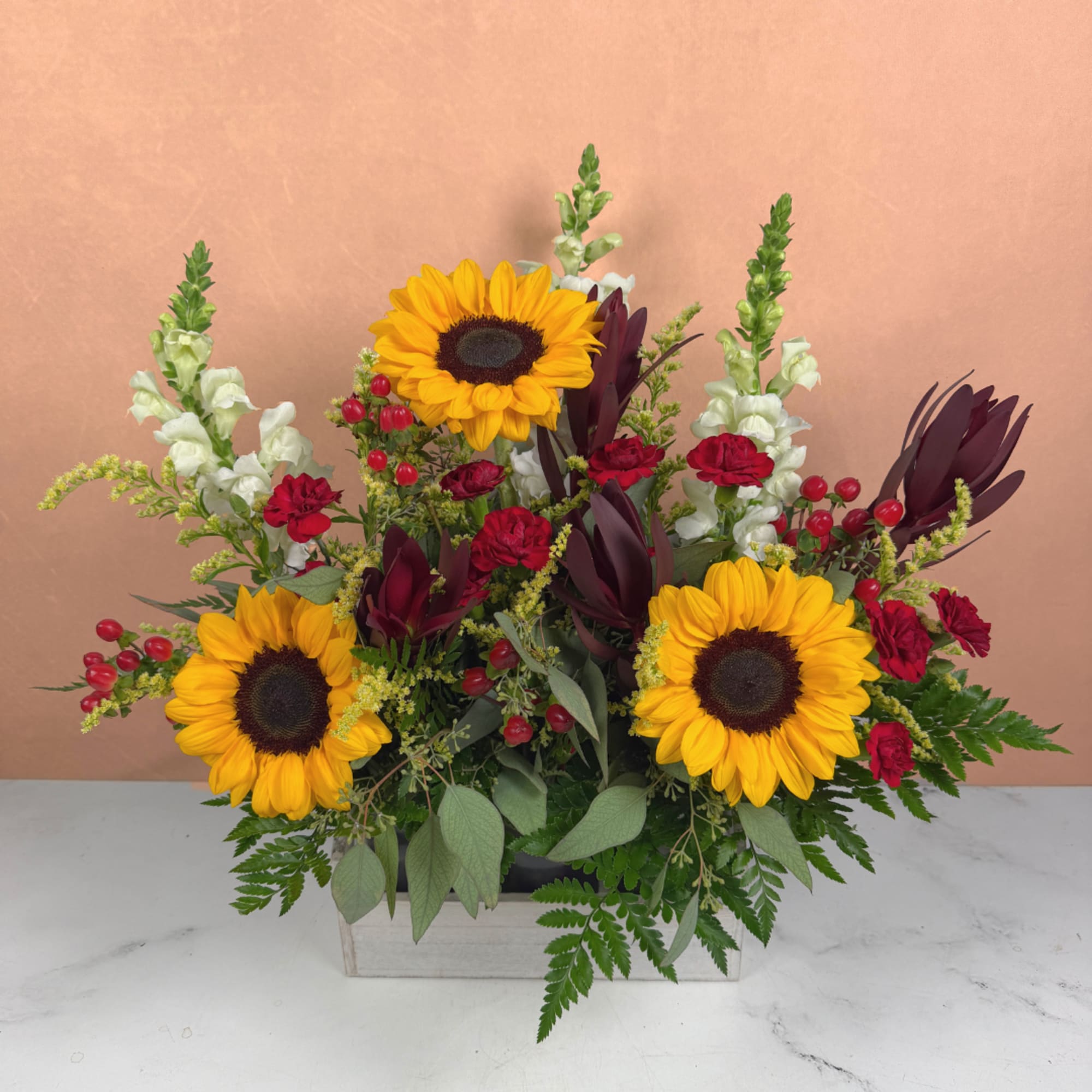 Sunflower arrangement with red carnations and white snapdragons in a wooden box
