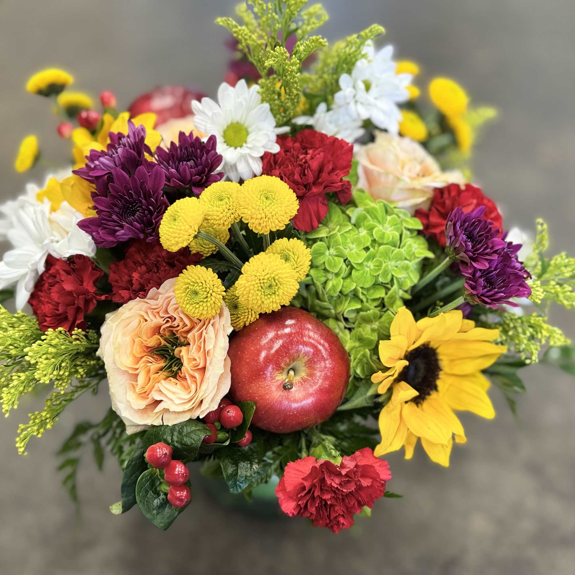 Colorful mixed bouquet with roses, chrysanthemums, carnations, and a red apple