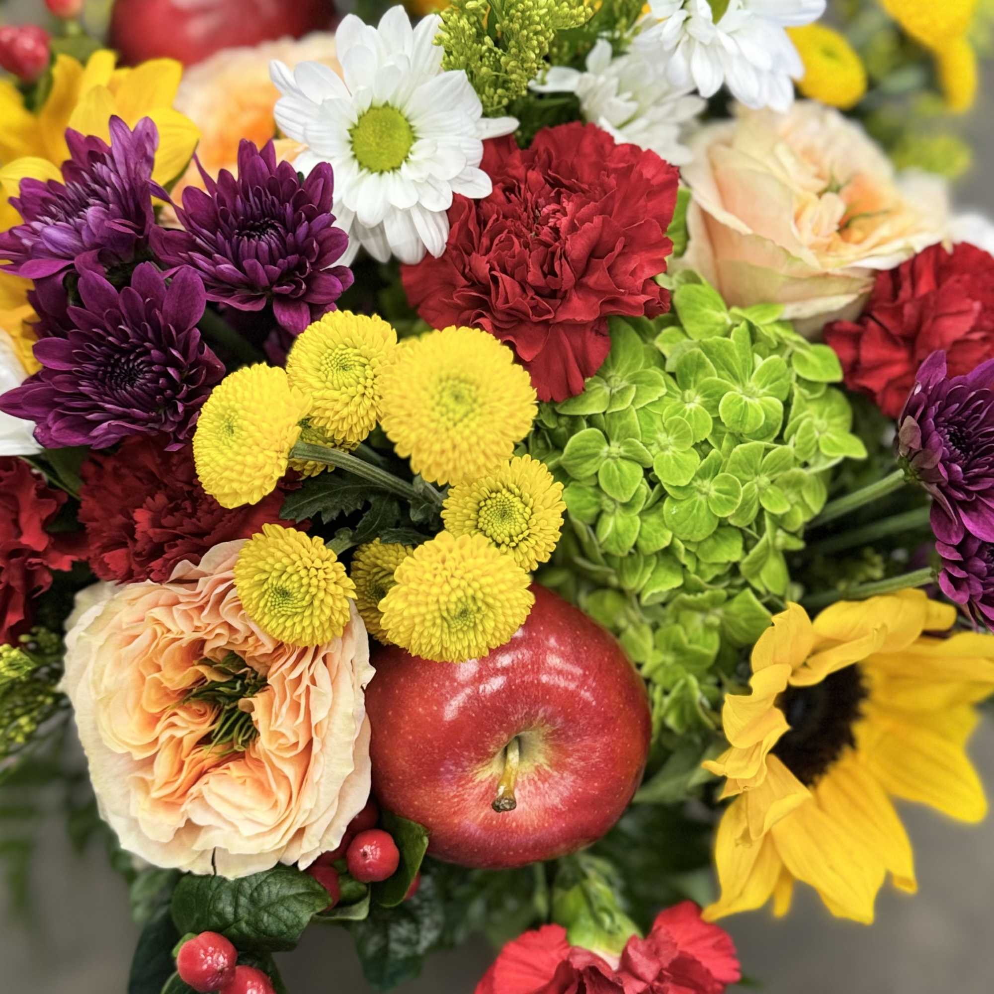 Colorful bouquet with apples, chrysanthemums, carnations, and sunflowers