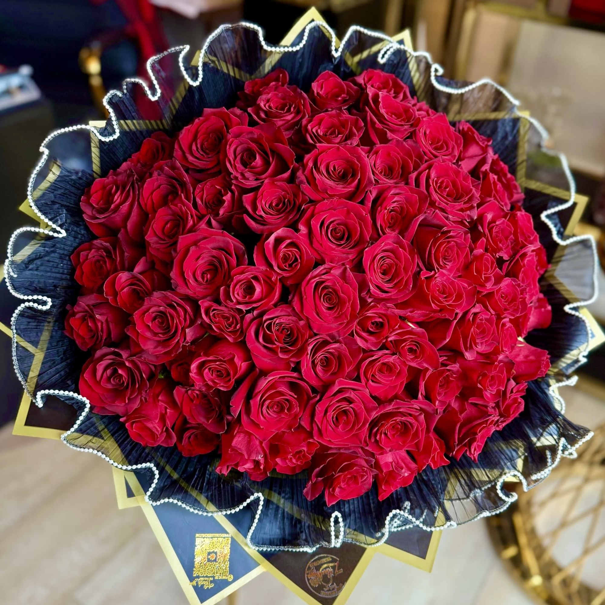Large bouquet of red roses wrapped in dark paper