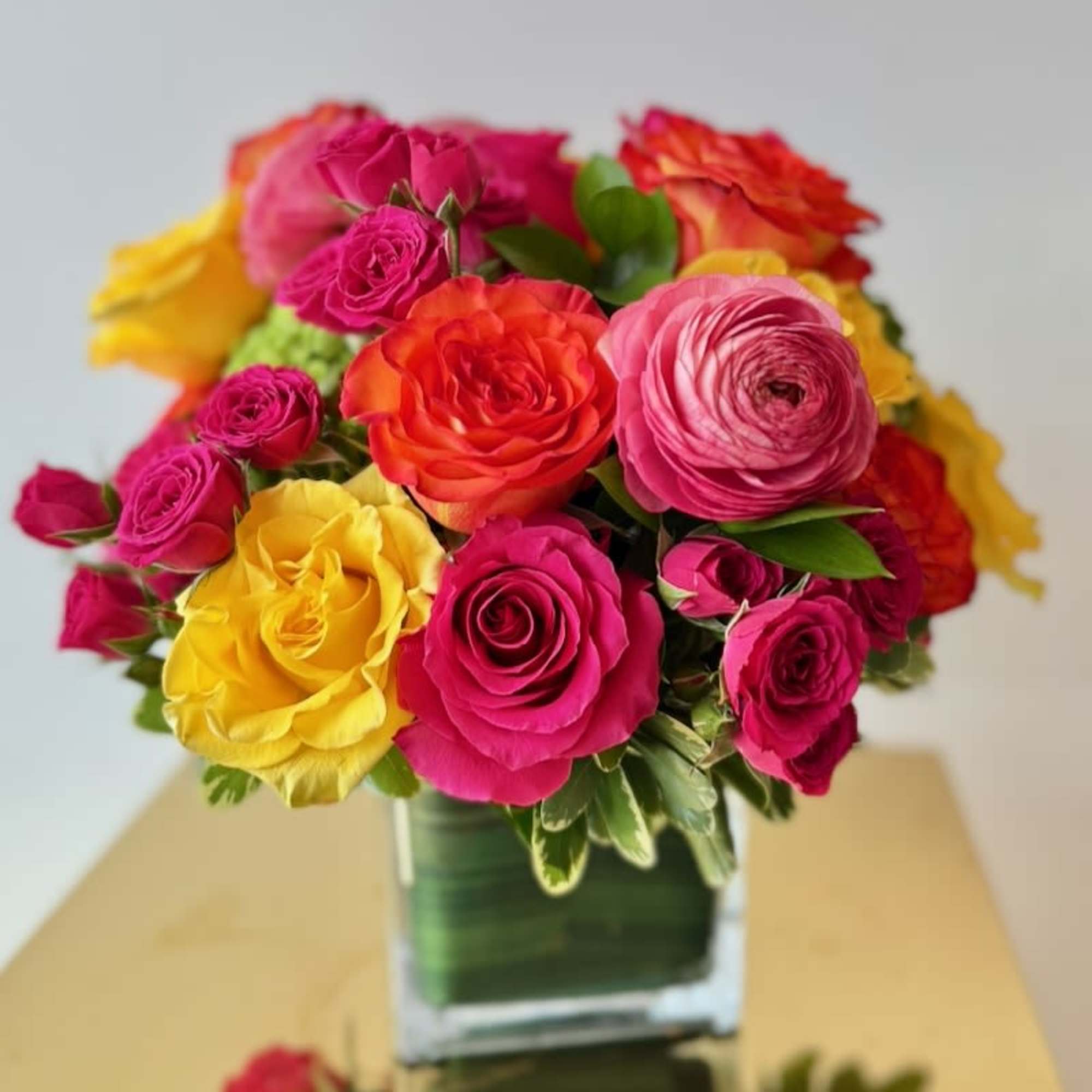 Bouquet of bright roses in a clear square vase