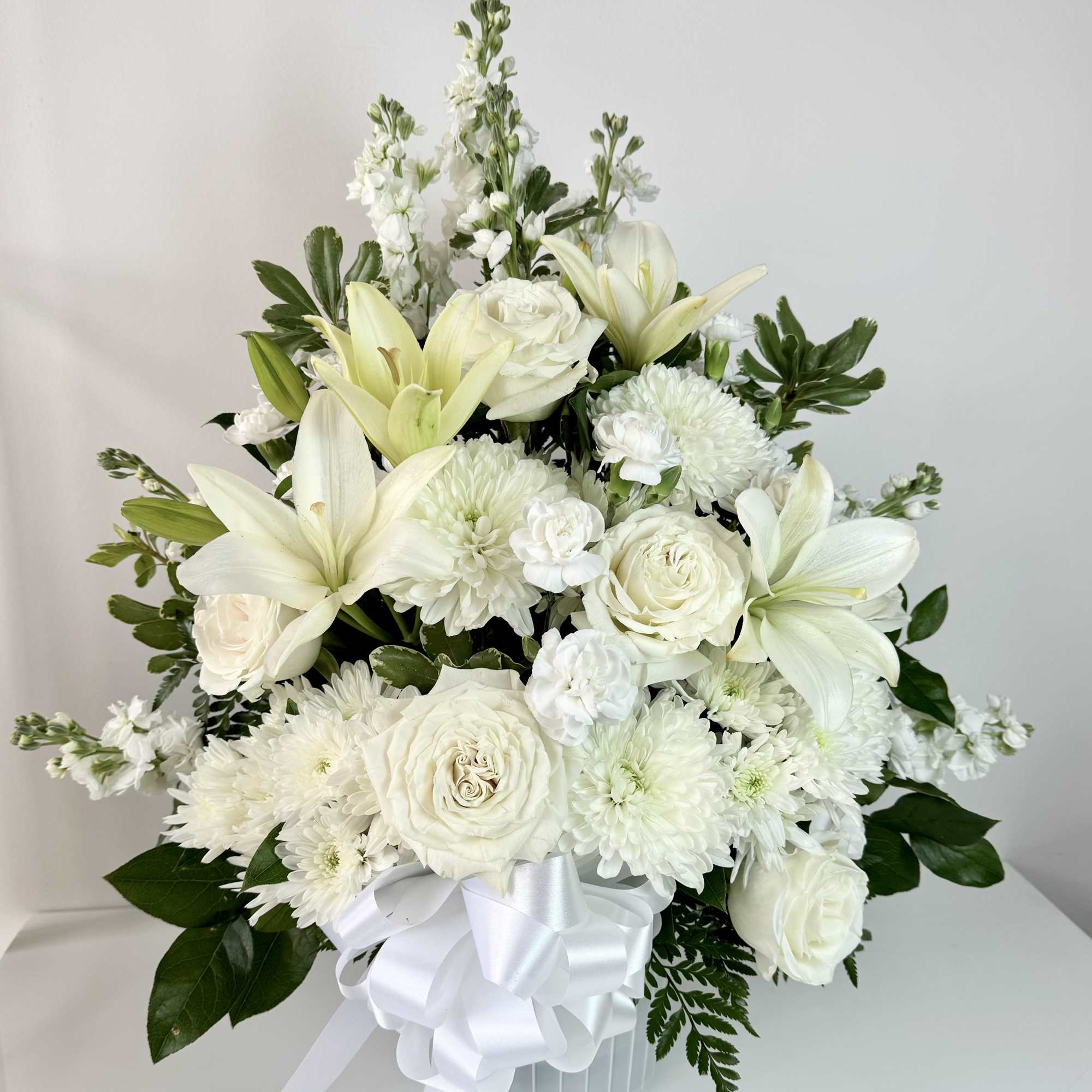 White floral arrangement with lilies, roses, and chrysanthemums in a white vase