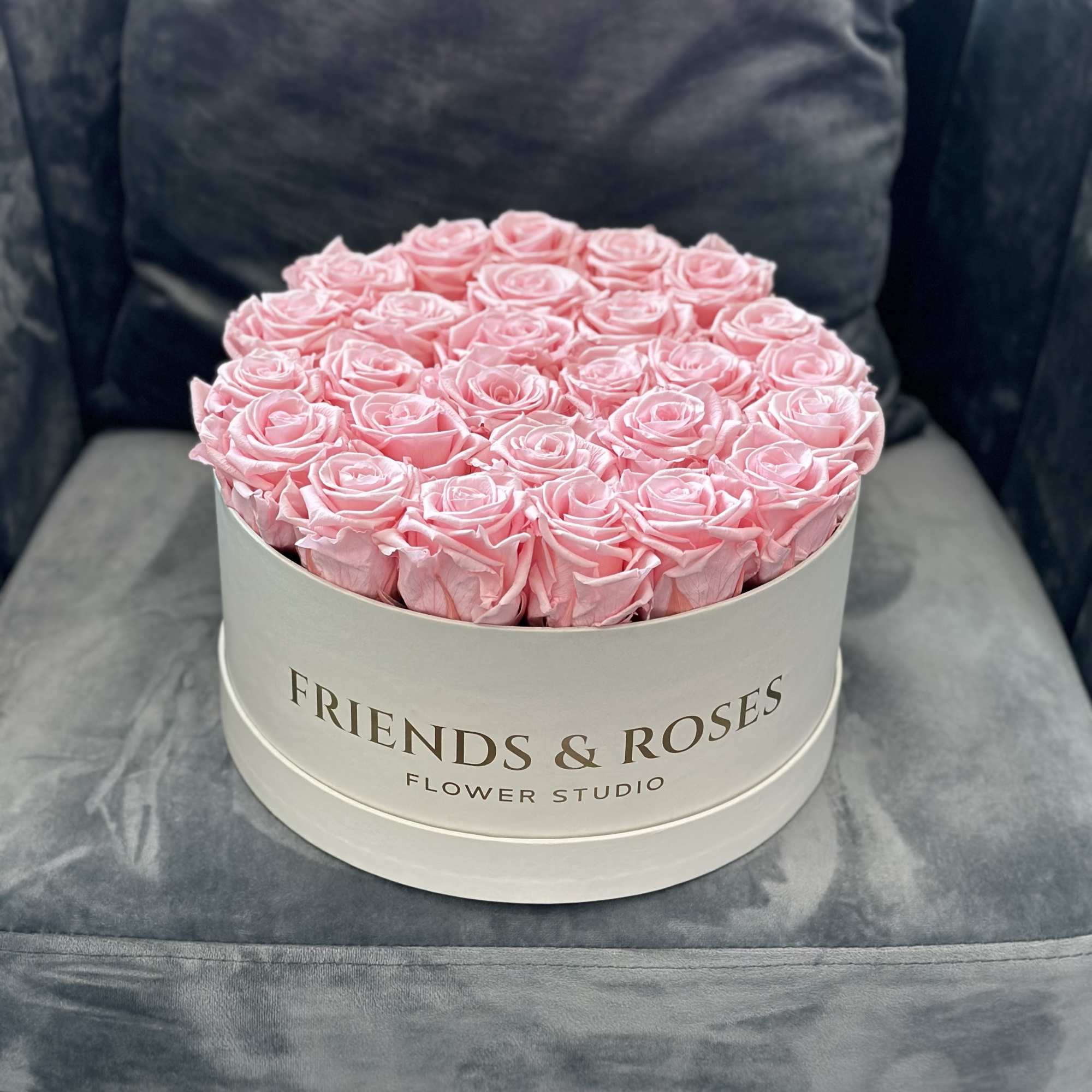 Round box of pink roses on a gray chair