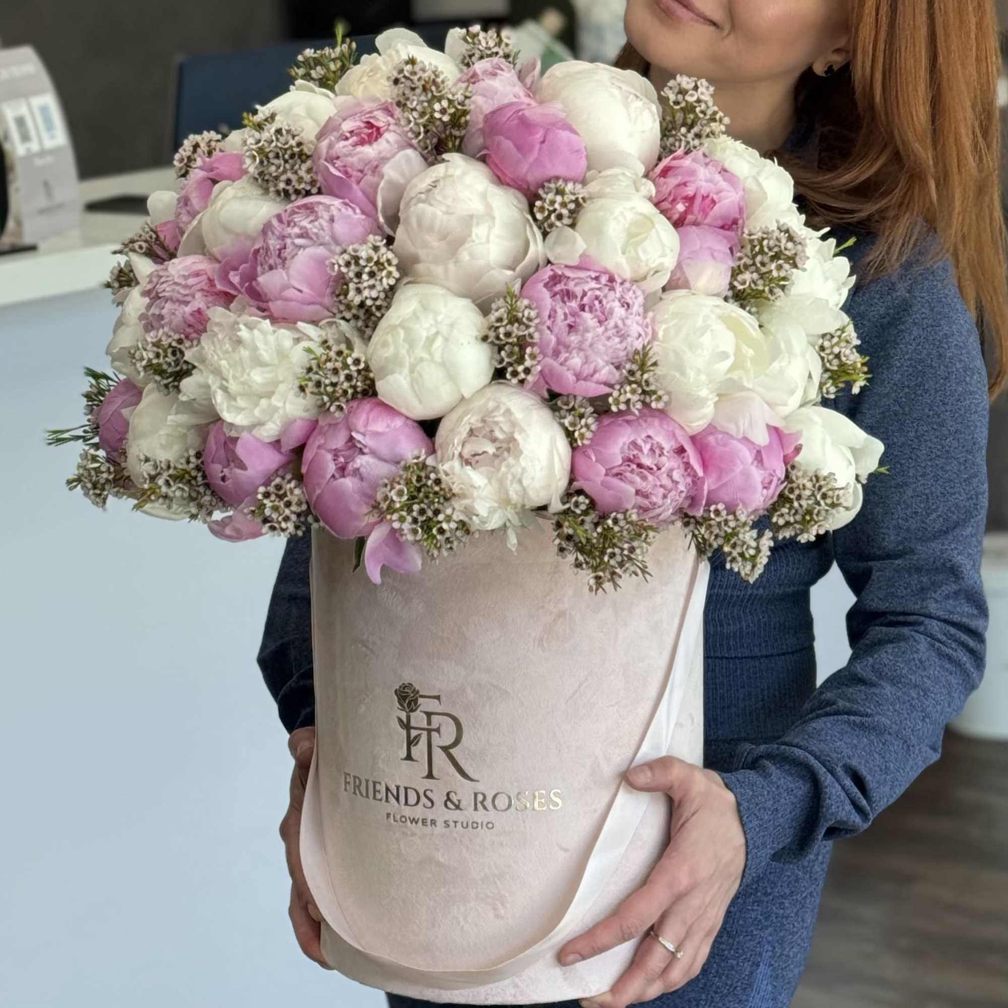 Pink and white peonies in a round hatbox