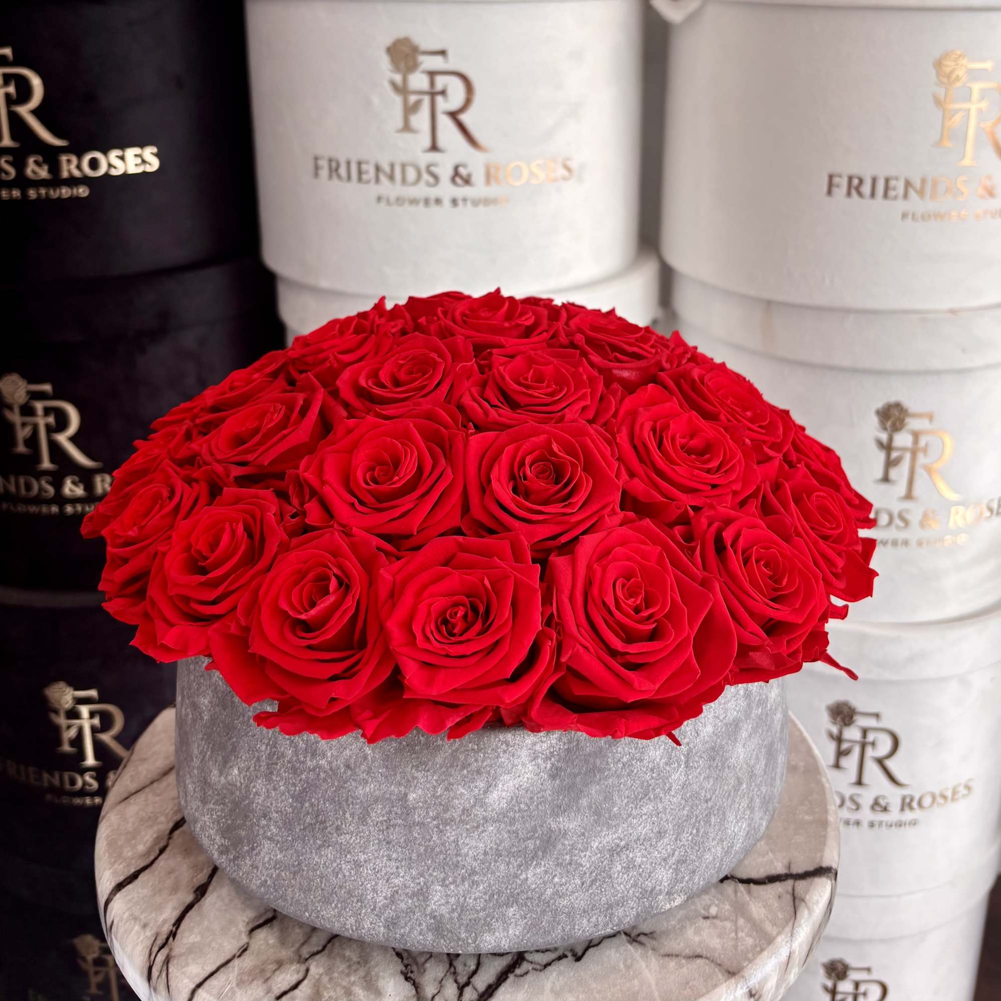Round box of red roses on a marble pedestal