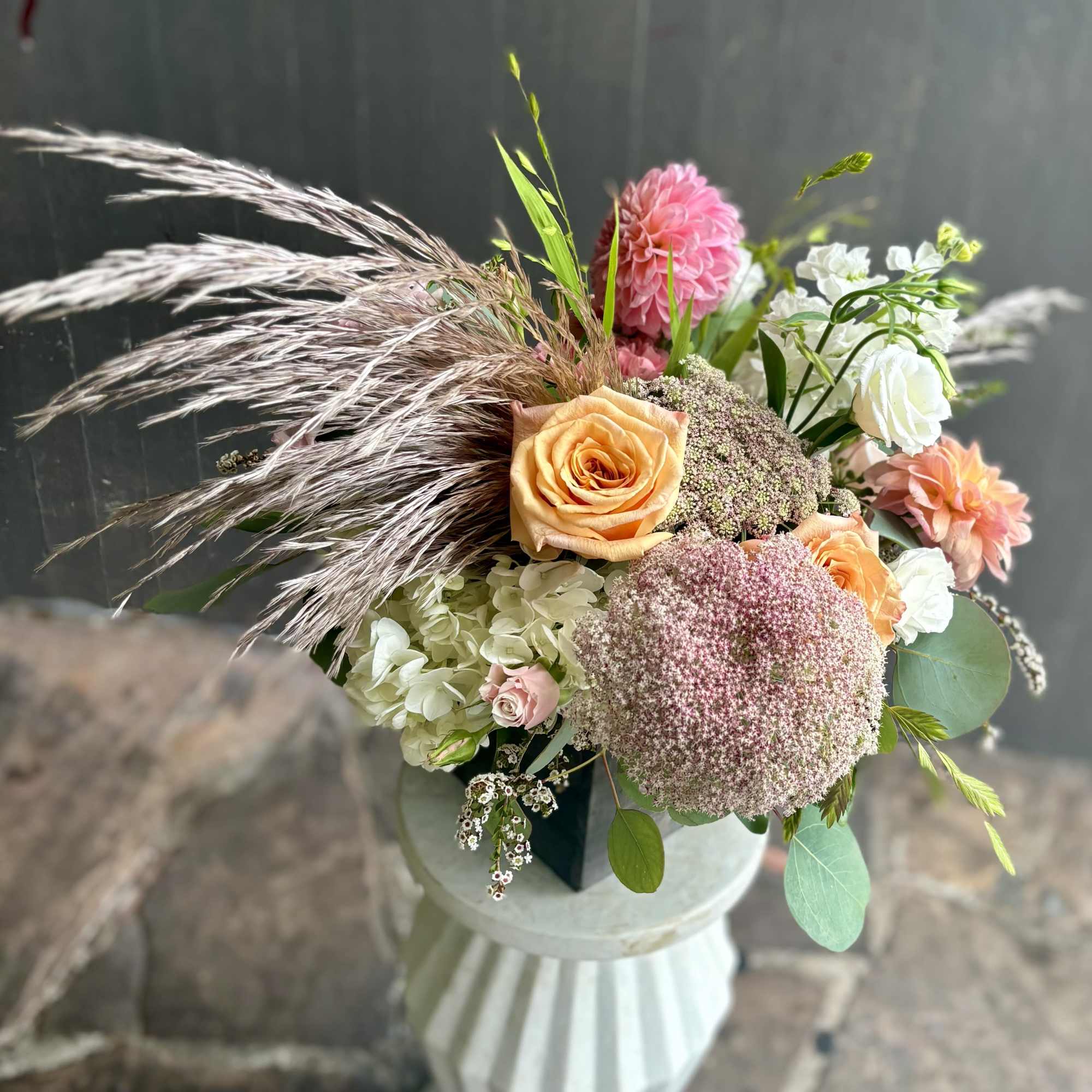 Mixed bouquet with peach roses, pink dahlias, white hydrangea, and dried grasses