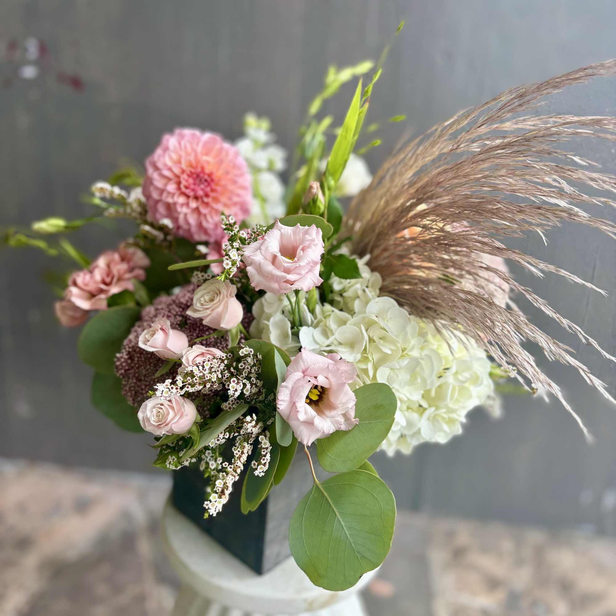 Pink and white mixed bouquet with roses, hydrangea, and dried grass in a vase