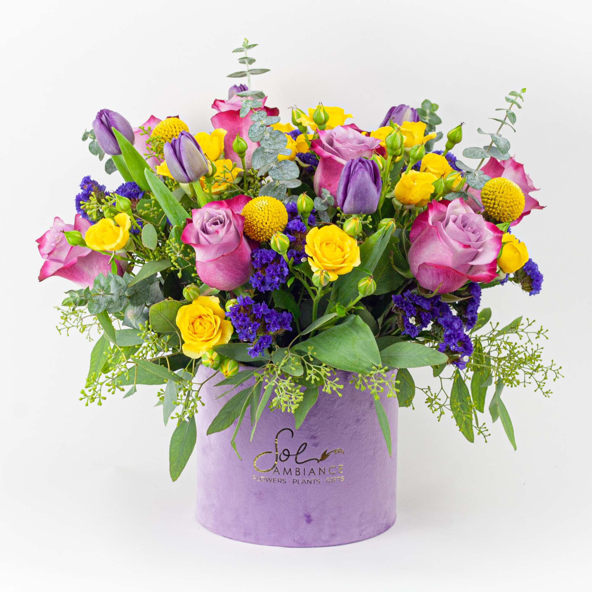 Mixed bouquet of pink, purple, and yellow flowers in a lavender box