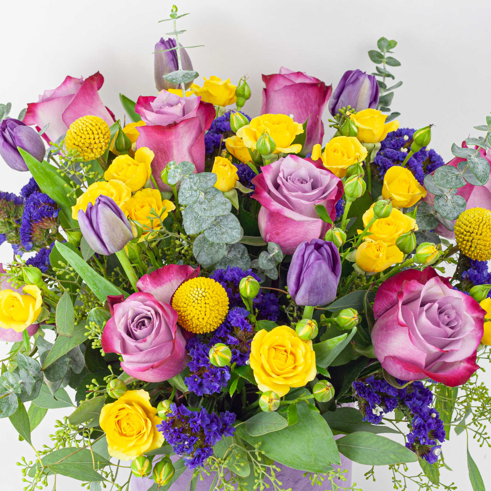 Bouquet of pink and yellow roses with purple tulips and filler flowers