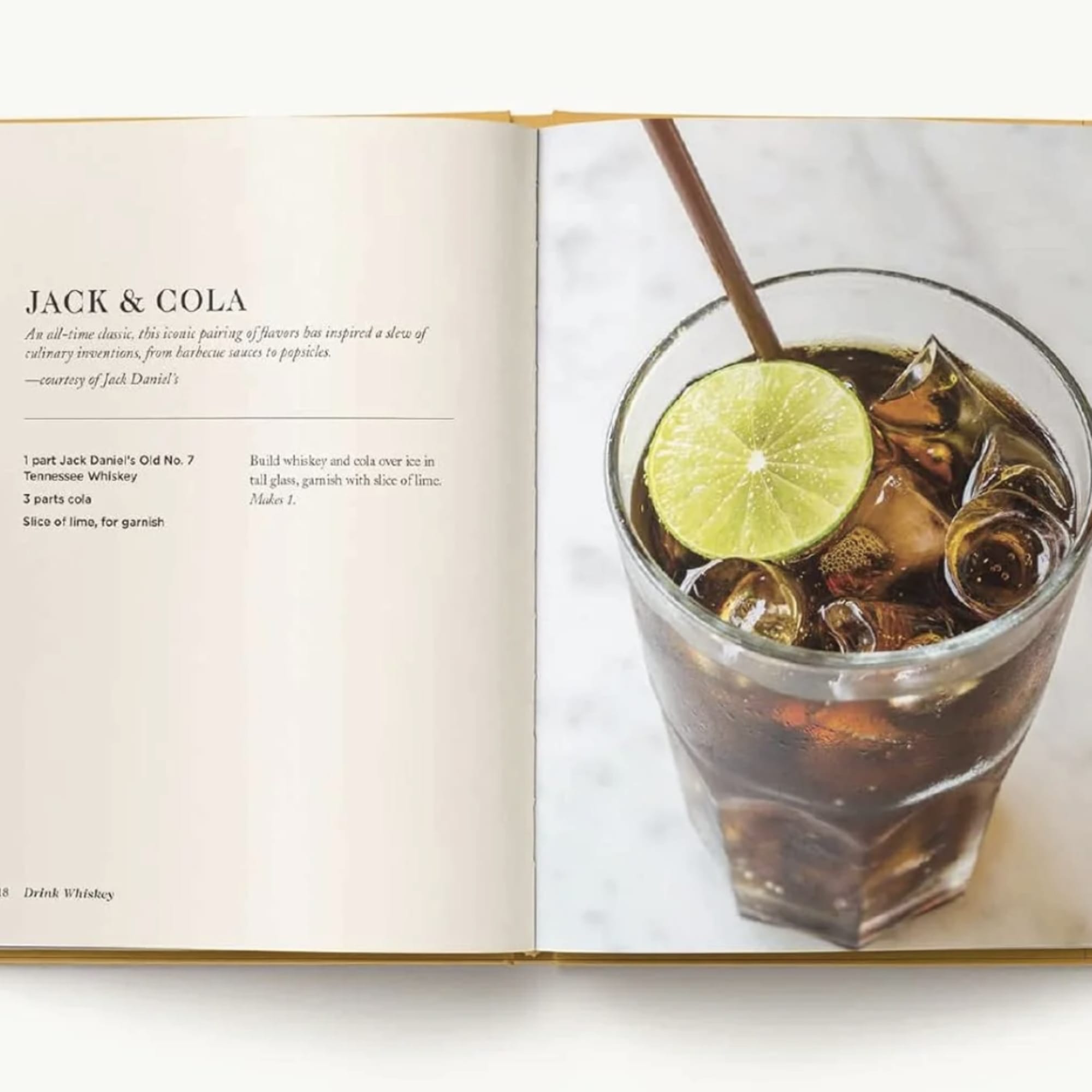 Open book showing a Jack and cola cocktail recipe and a glass of the drink