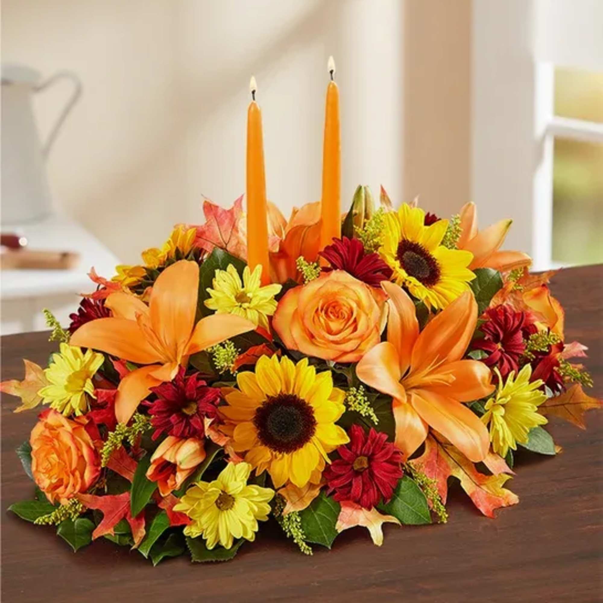 Autumn floral centerpiece with orange candles and mixed blooms on a table