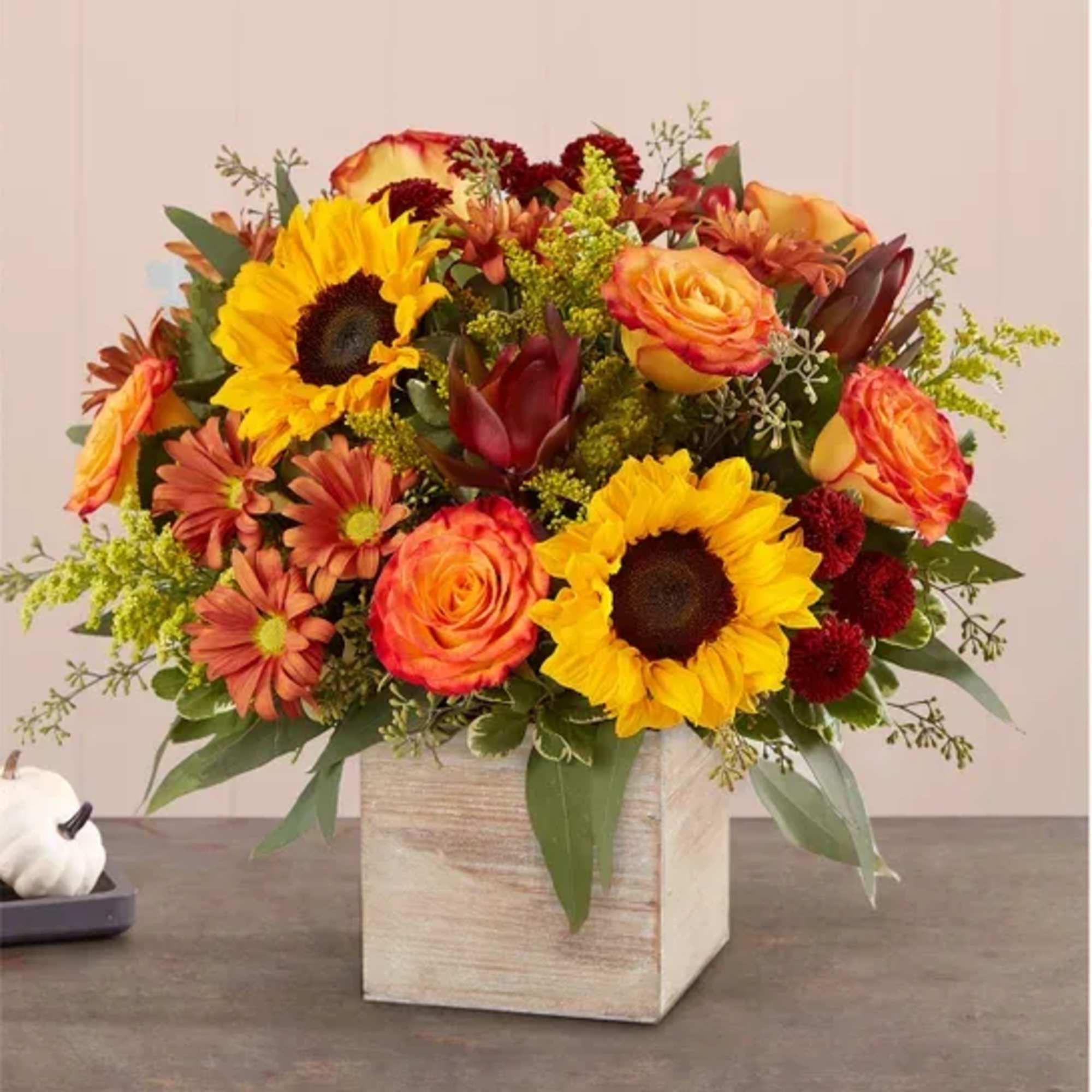 Bright mixed bouquet with sunflowers and roses in a square wooden vase