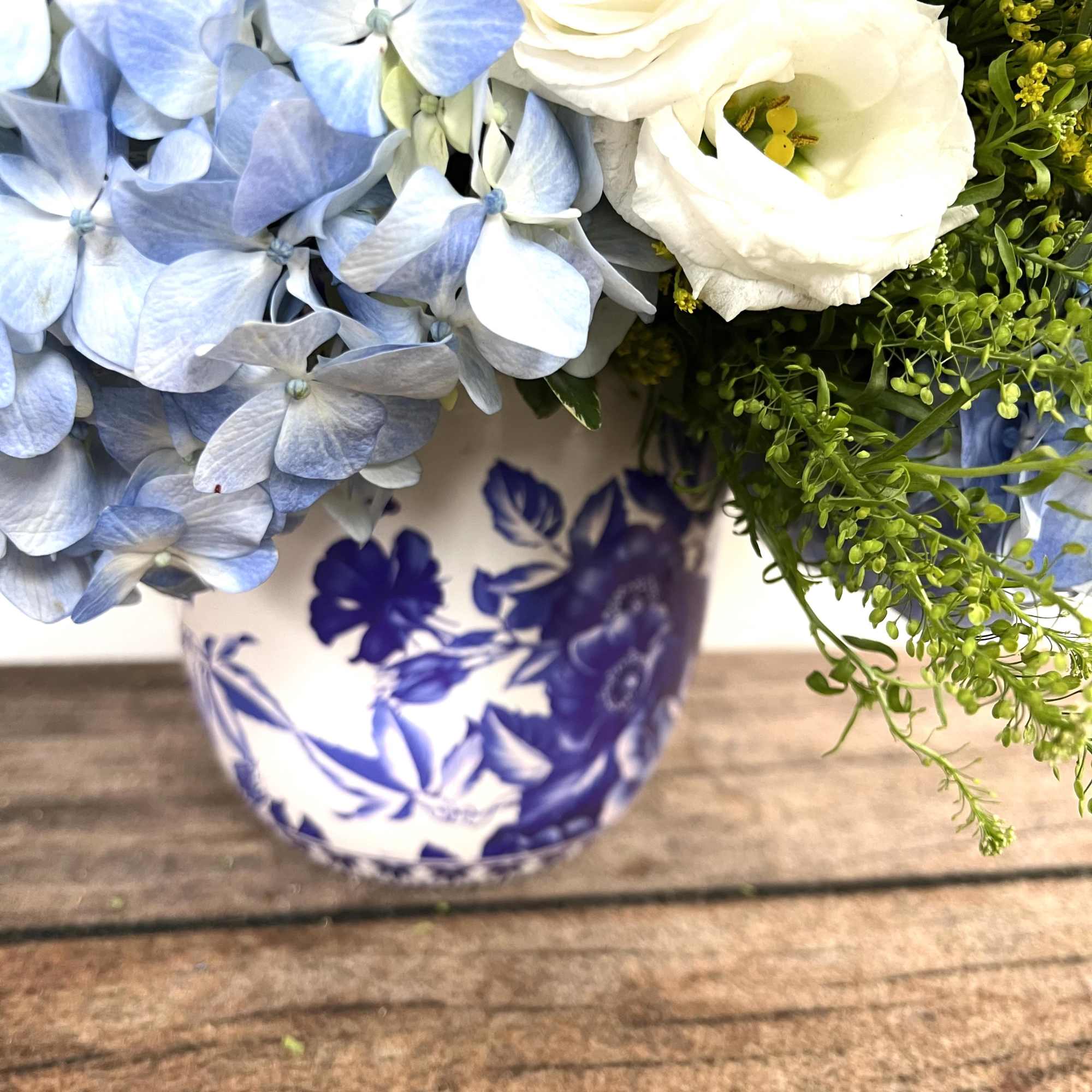 Blue hydrangeas and white lisianthus in a blue-and-white ceramic vase