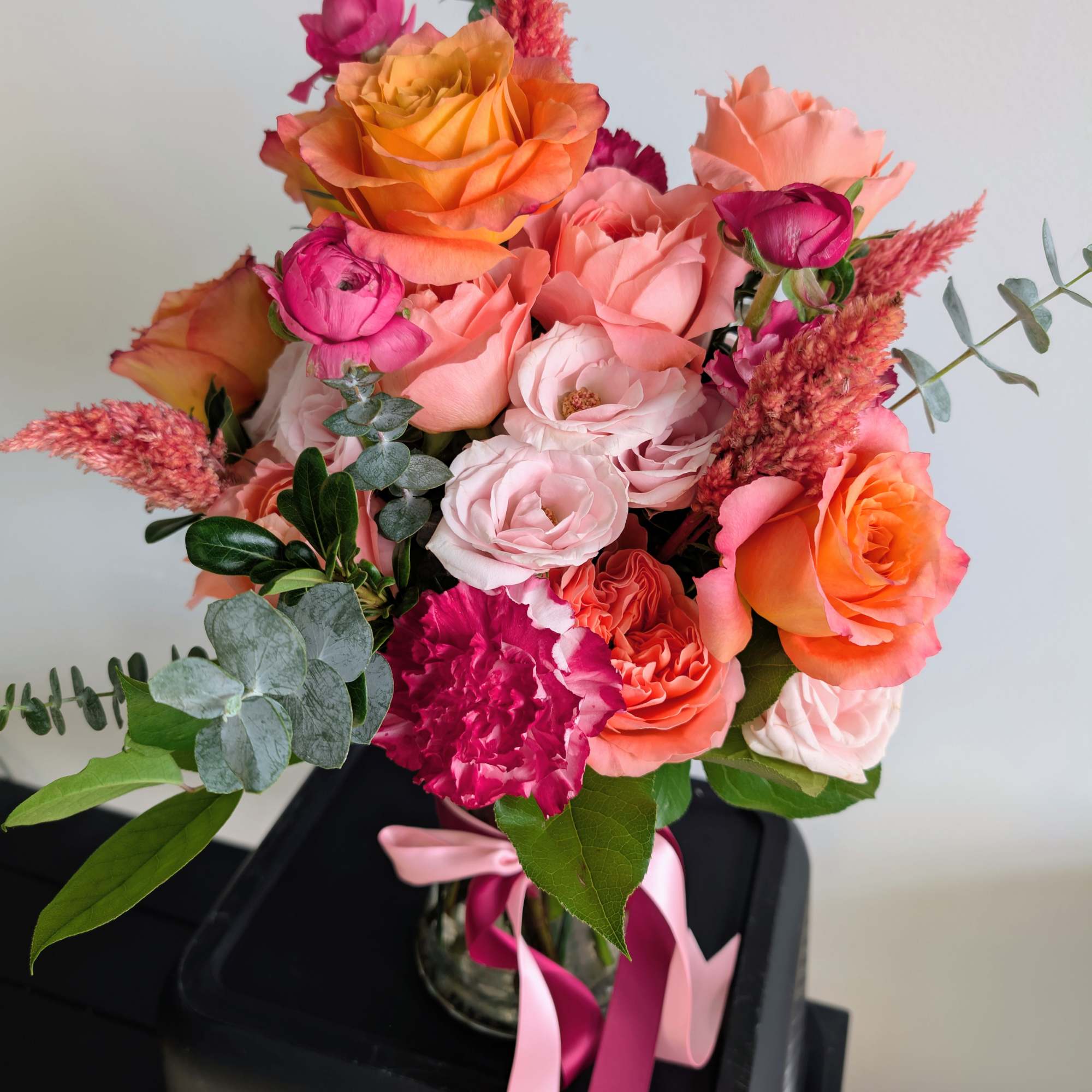 Bouquet of orange, pink, and peach roses in a glass vase