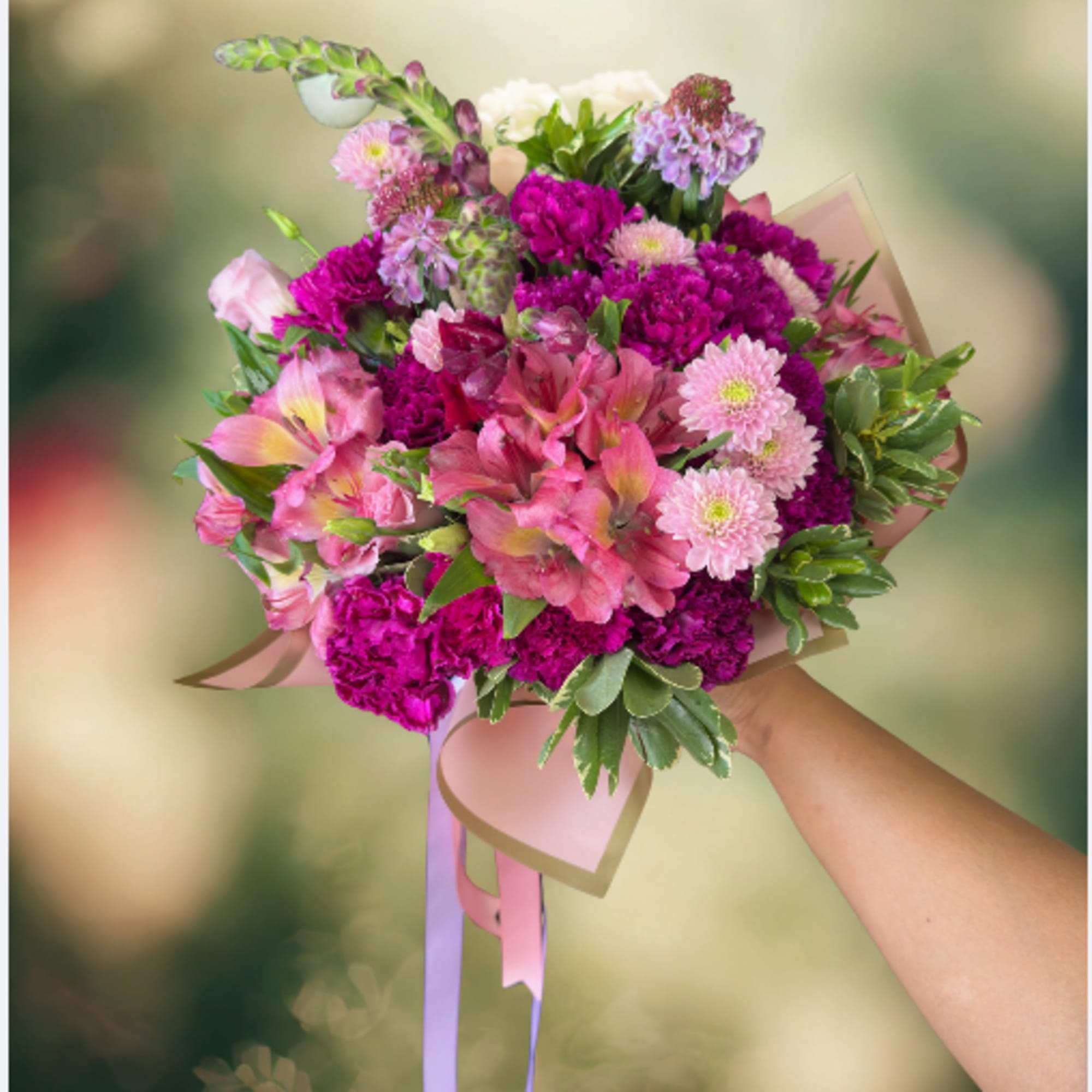 Handheld bouquet of pink and purple flowers with ribbon wrap