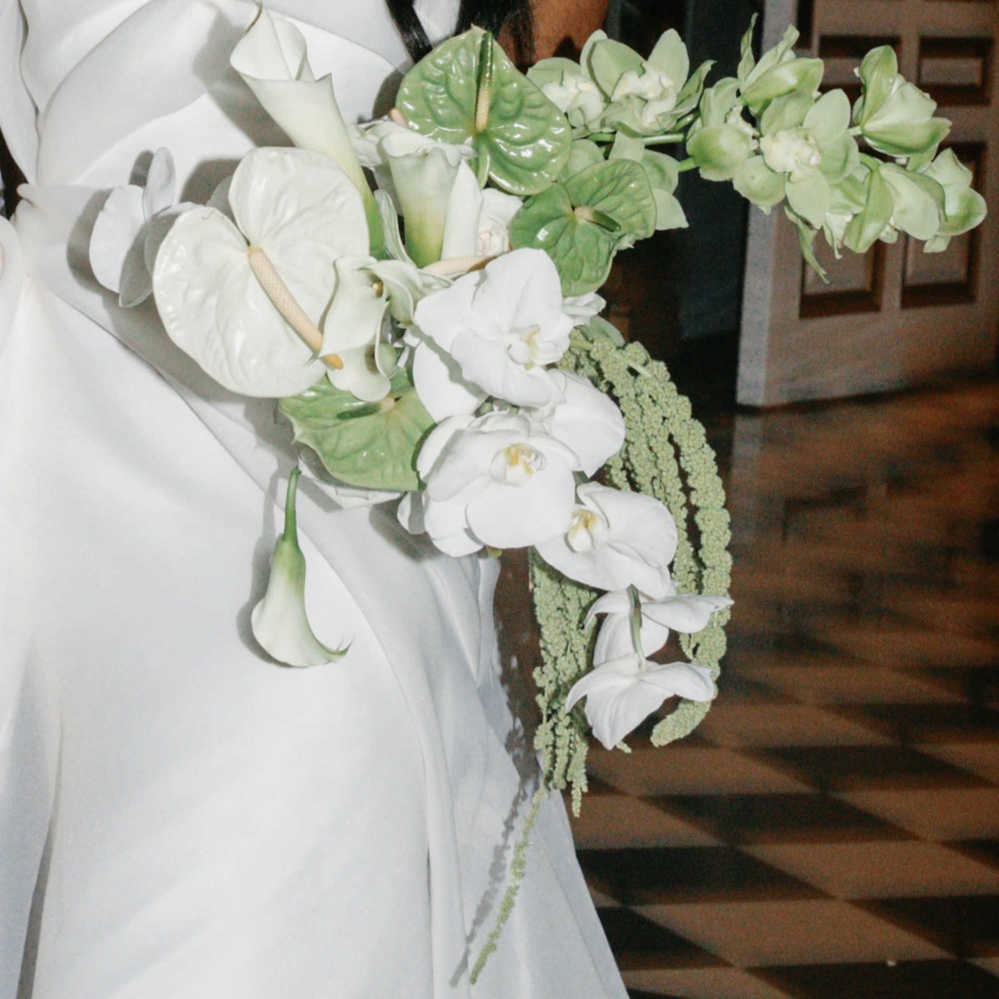 Modern cascading bridal bouquet of white calla lilies, orchids, and green tropical blooms.
