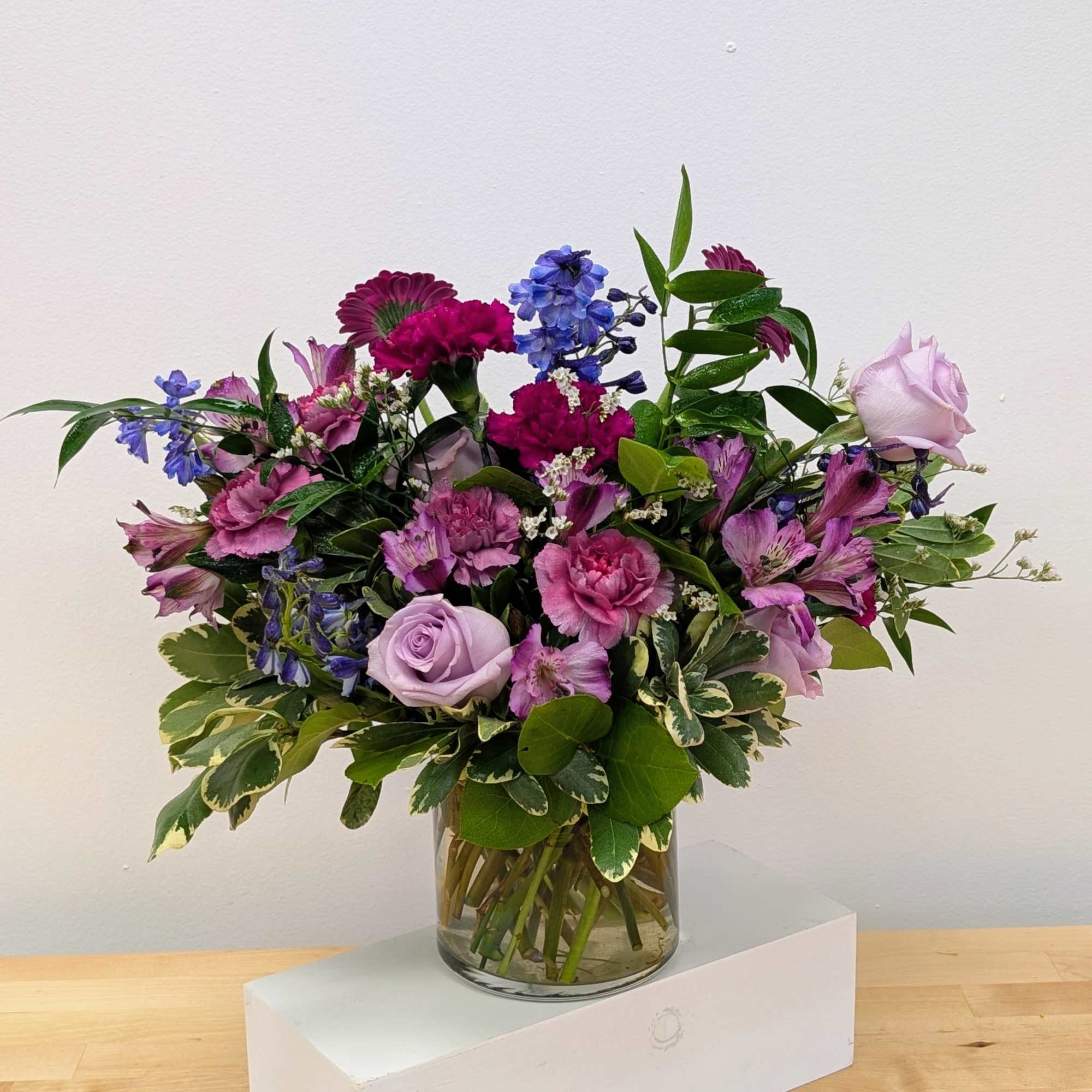 Mixed pink and purple flower arrangement in a glass vase