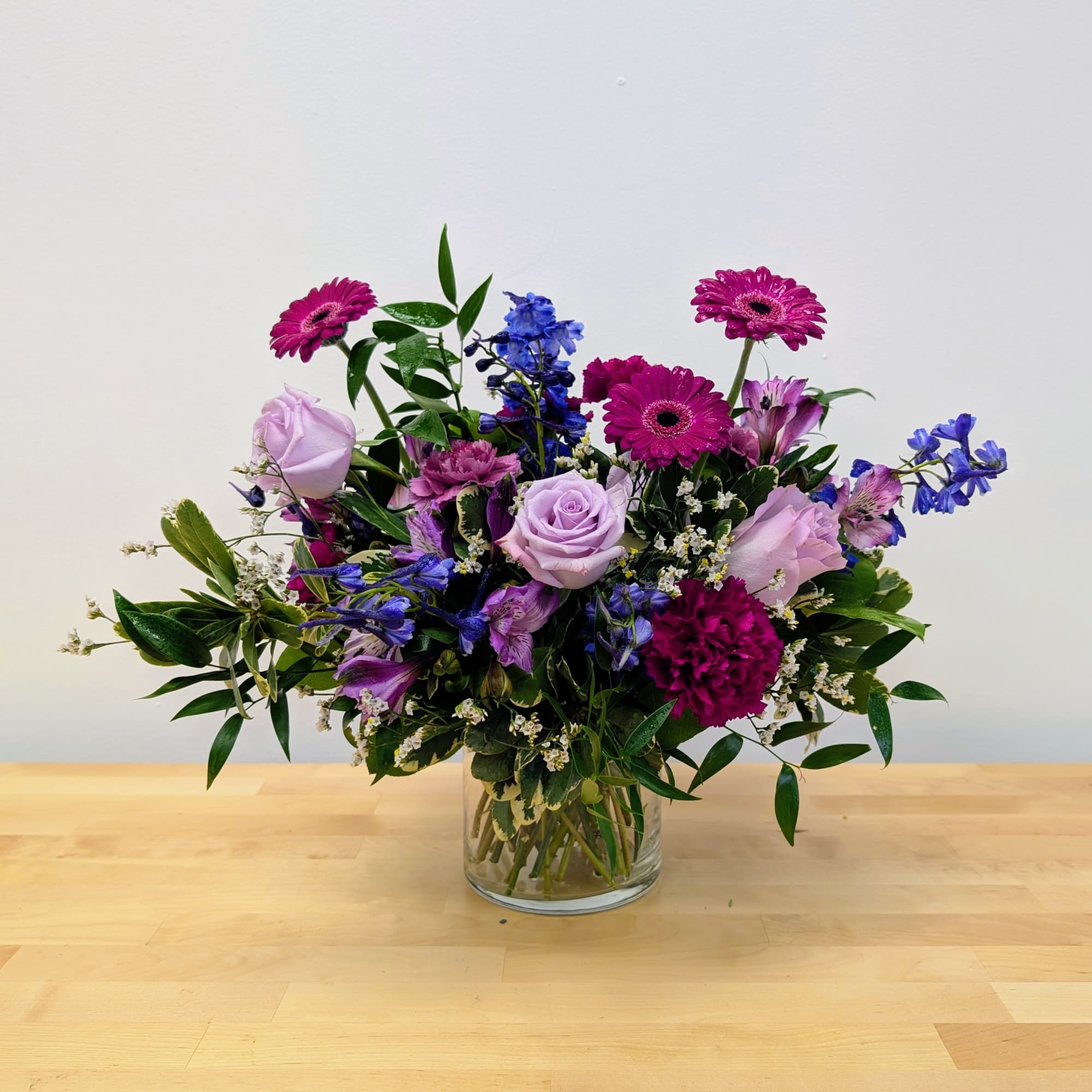 Mixed bouquet of purple and blue flowers in a glass vase