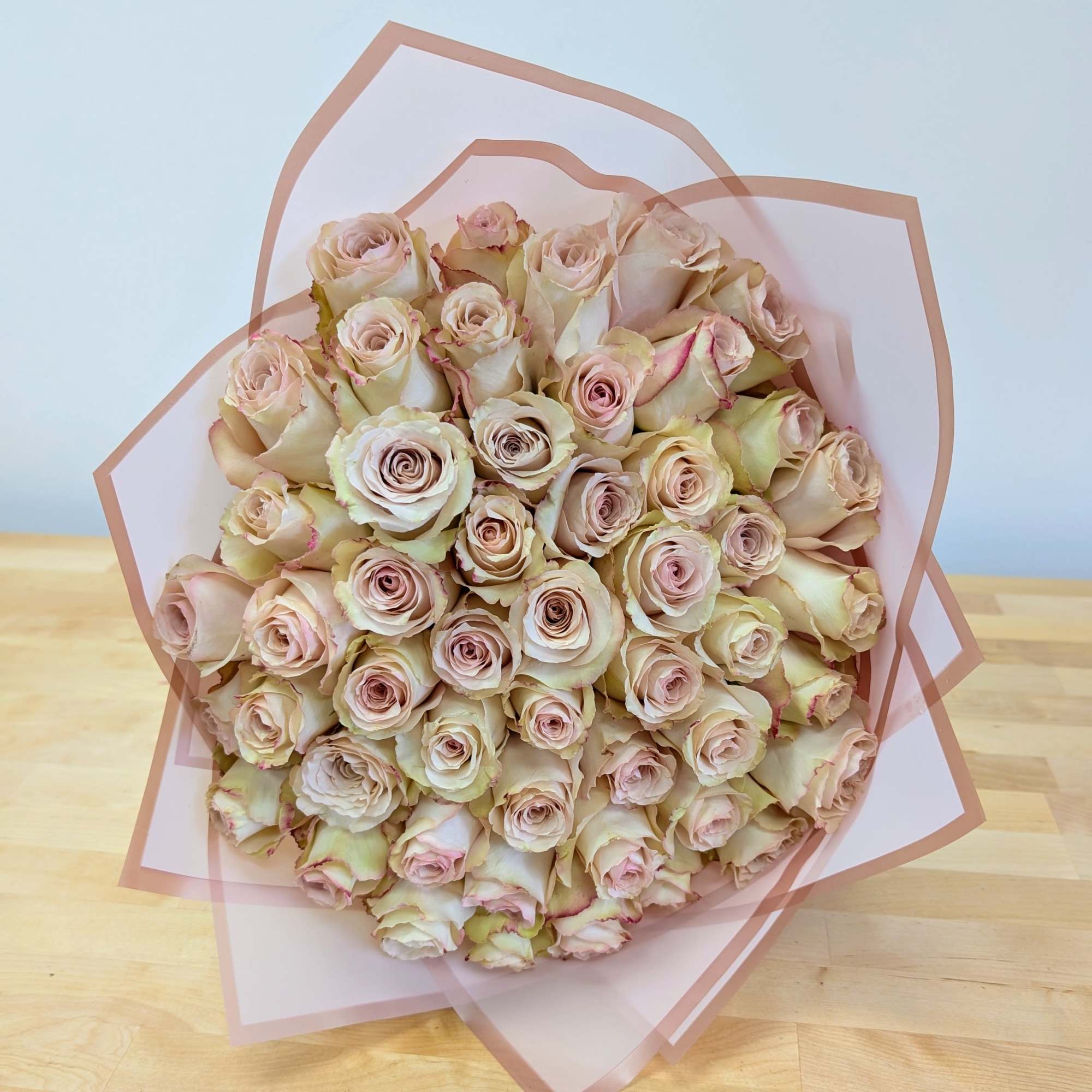 Bouquet of pale pink roses wrapped in translucent pink paper