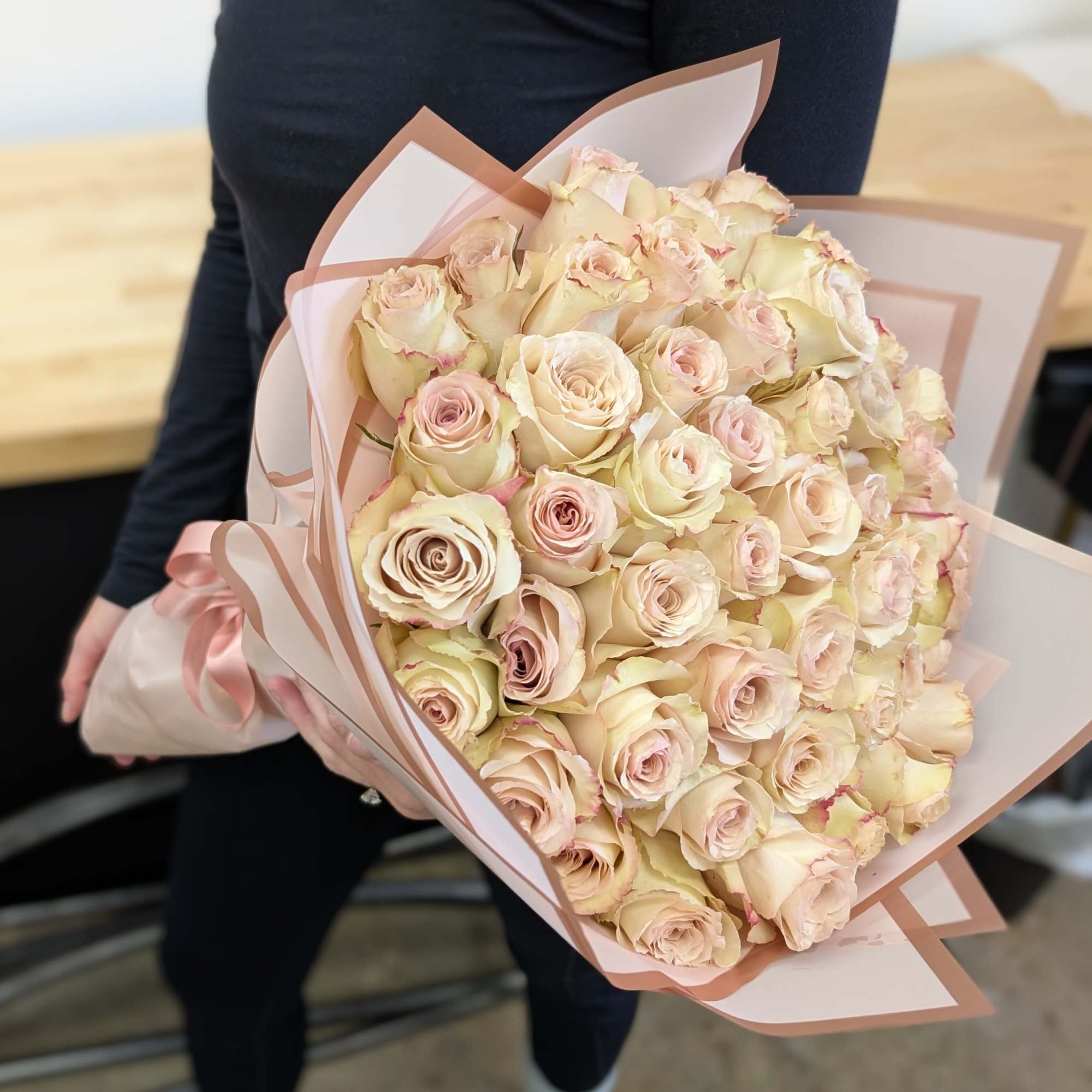 Large bouquet of pale pink and cream roses wrapped in blush paper