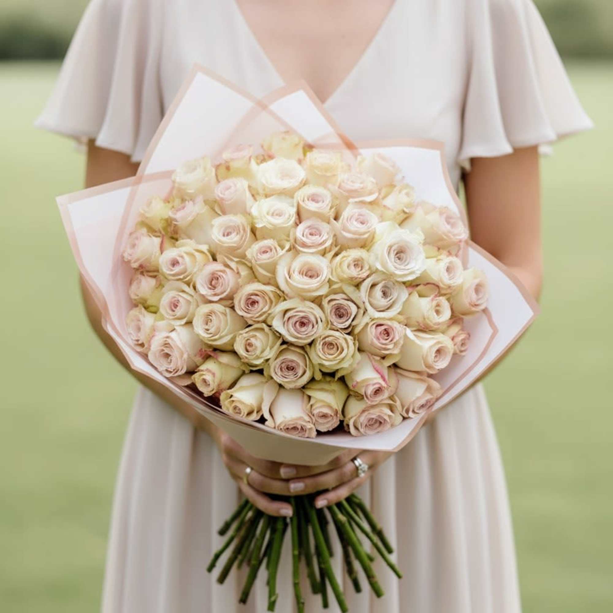 Woman holding a large bouquet of pale pink and cream roses