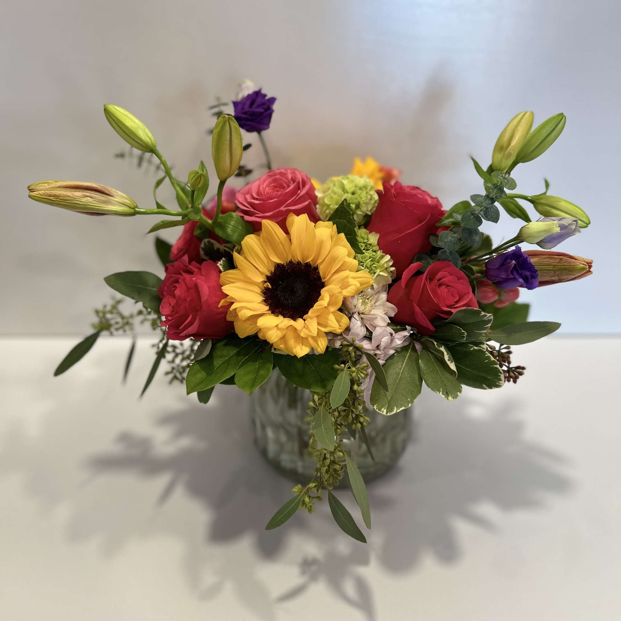 Mixed bouquet with a sunflower, pink roses, and purple blooms in a glass vase, photo 4 of 4