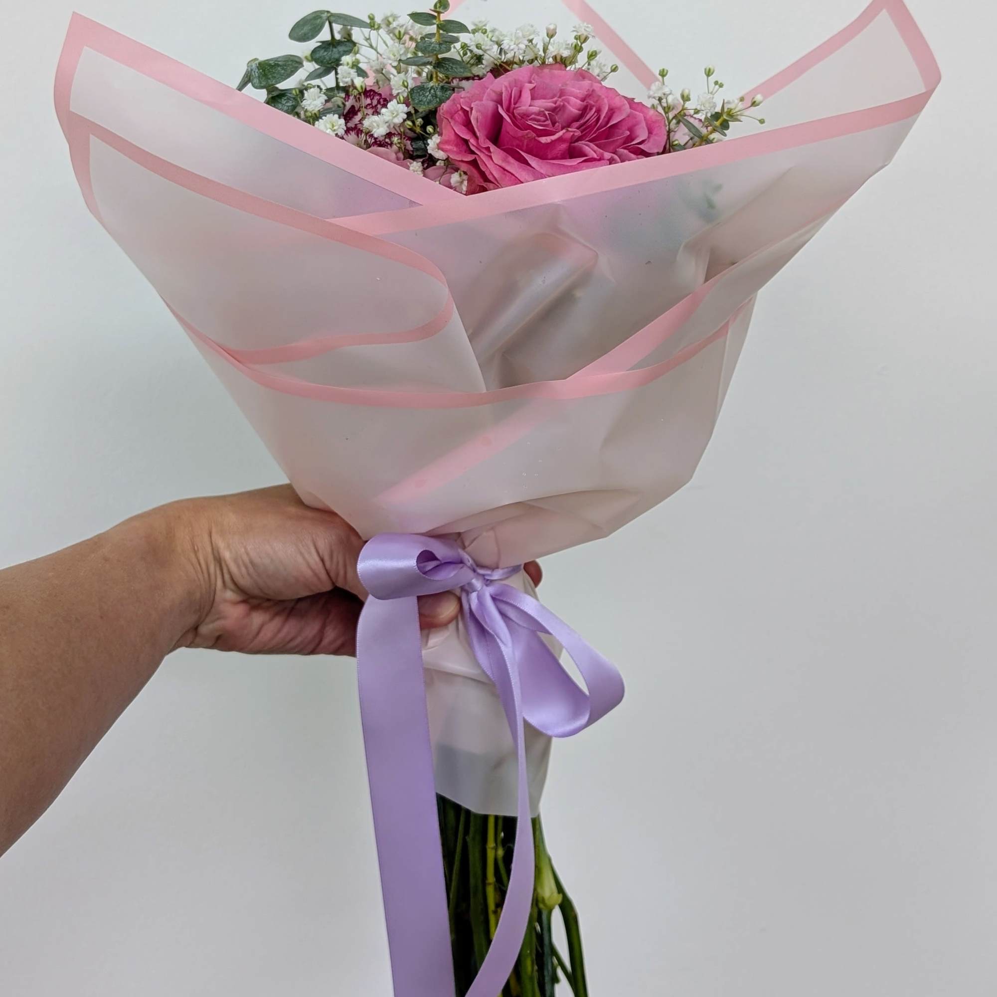Pink rose bouquet wrapped in translucent paper with a lavender ribbon, photo 2 of 3