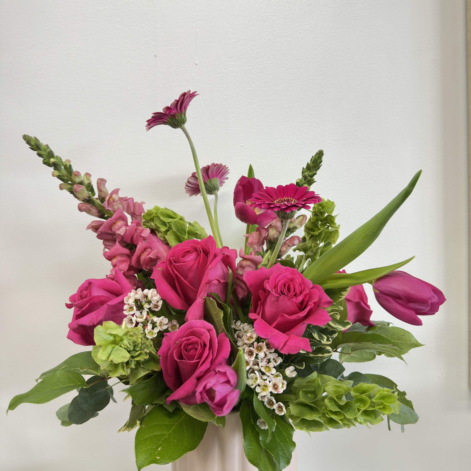 Pink roses and tulips in a pale pink vase