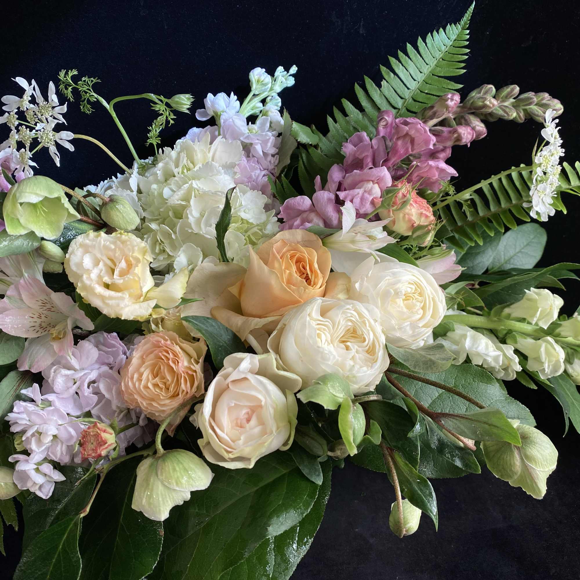 Mixed bouquet of peach, white, and pink flowers on a black background