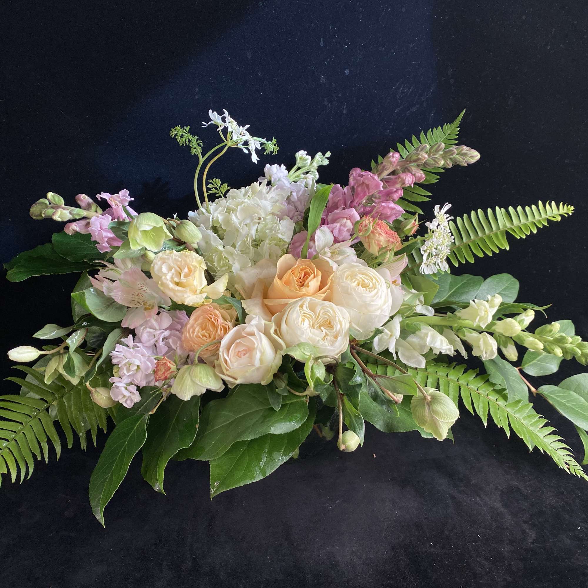 Low floral arrangement with peach and white roses and pink blooms